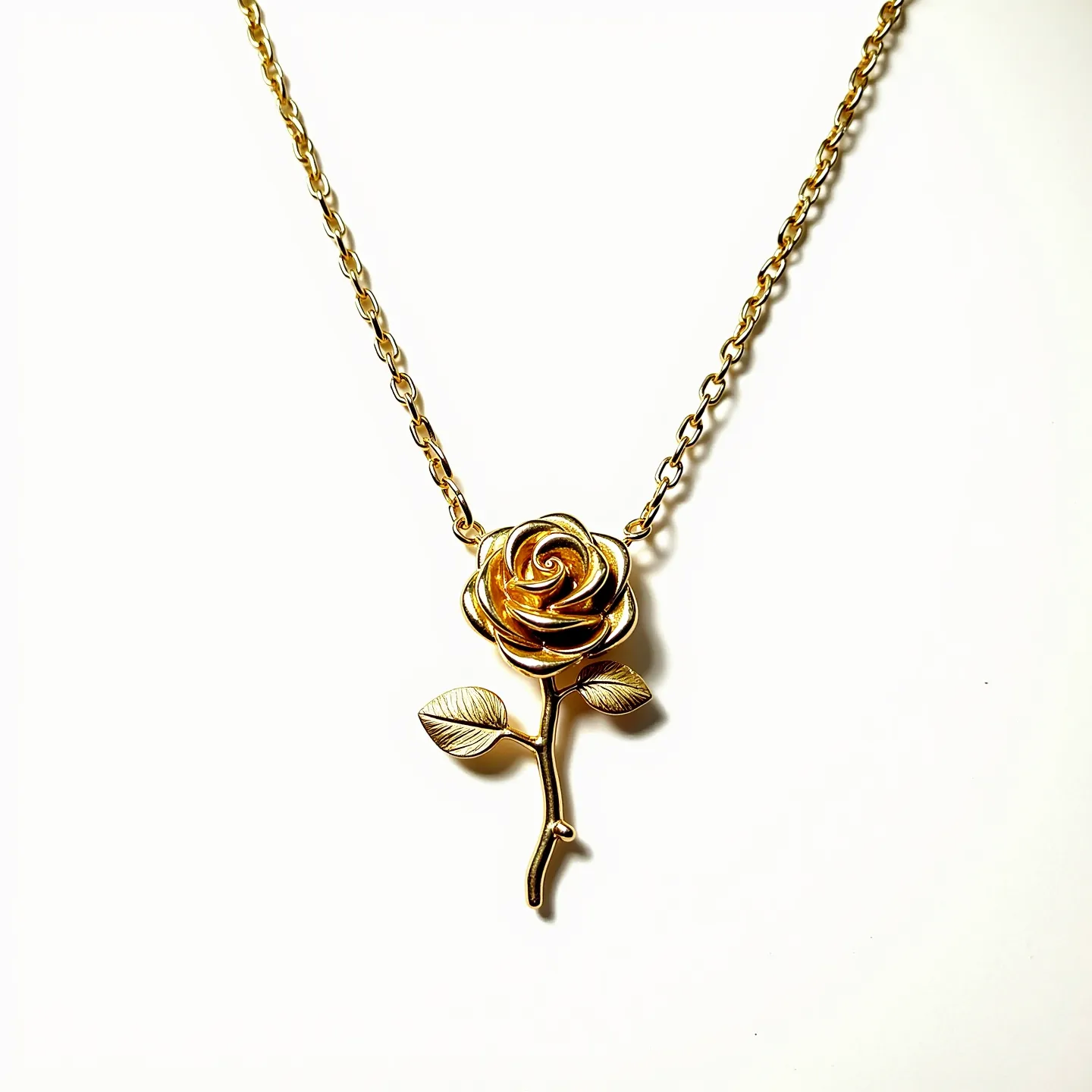 This rose necklace features a beautifully crafted rose pendant, likely made from metal with a polished gold-tone finish. The pendant is intricately designed, showcasing detailed petals and leaves attached to a delicate stem. The necklace itself consists of a classic cable chain, which complements the pendant's elegant design. There are no additional gems or stones present in the composition. The necklace is most likely secured with a standard lobster clasp, ensuring both style and functionality in its design.