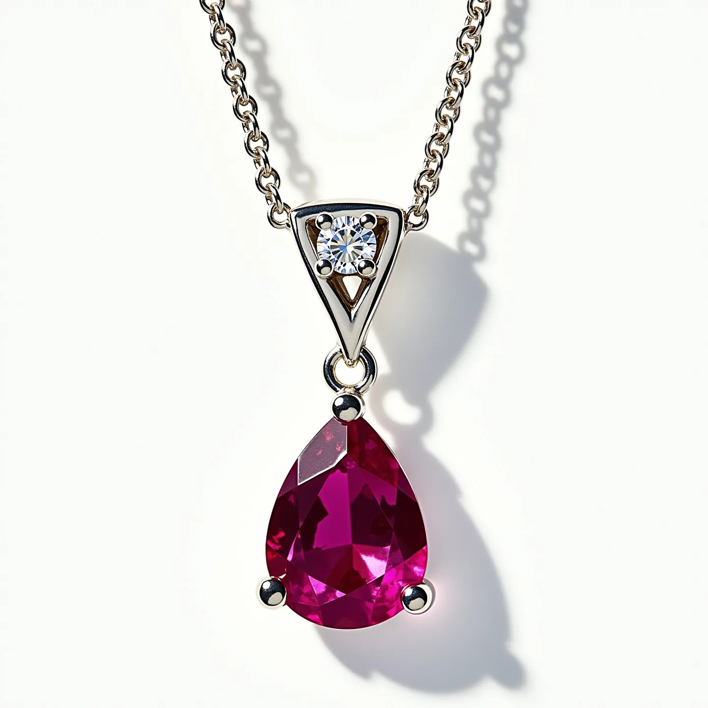 This ruby necklace features a striking pear-shaped ruby as the central gem, set in a three-prong setting that accentuates its rich red hue. Above the ruby, there is a triangular setting that holds a round-cut diamond, adding an elegant sparkle to the piece. The necklace is crafted with a delicate metal chain, likely made of gold or platinum, which complements the luxurious feel of the gemstones. The pendant design showcases a harmonious blend of modern and classic styles, making it a versatile accessory for various occasions.