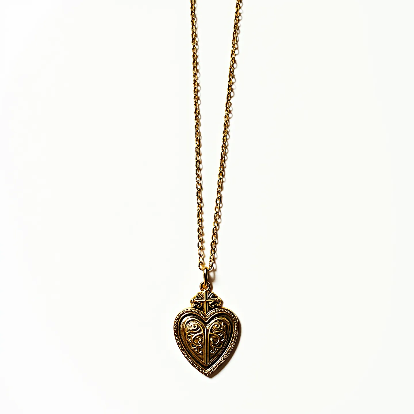 This sacred heart necklace features an ornate heart-shaped pendant crafted from gold-toned metal, showcasing intricate filigree detailing that adds a touch of elegance and vintage charm. The pendant is attached to a matching fine link chain that complements its design, and the attachment appears to be a small loop at the top of the heart. The necklace likely uses a standard clasp for securing it around the neck, although the particular type of clasp is not visible. The design, with its smooth curves and delicate patterns, imbues the piece with a sense of timeless spirituality and artistic craftsmanship.