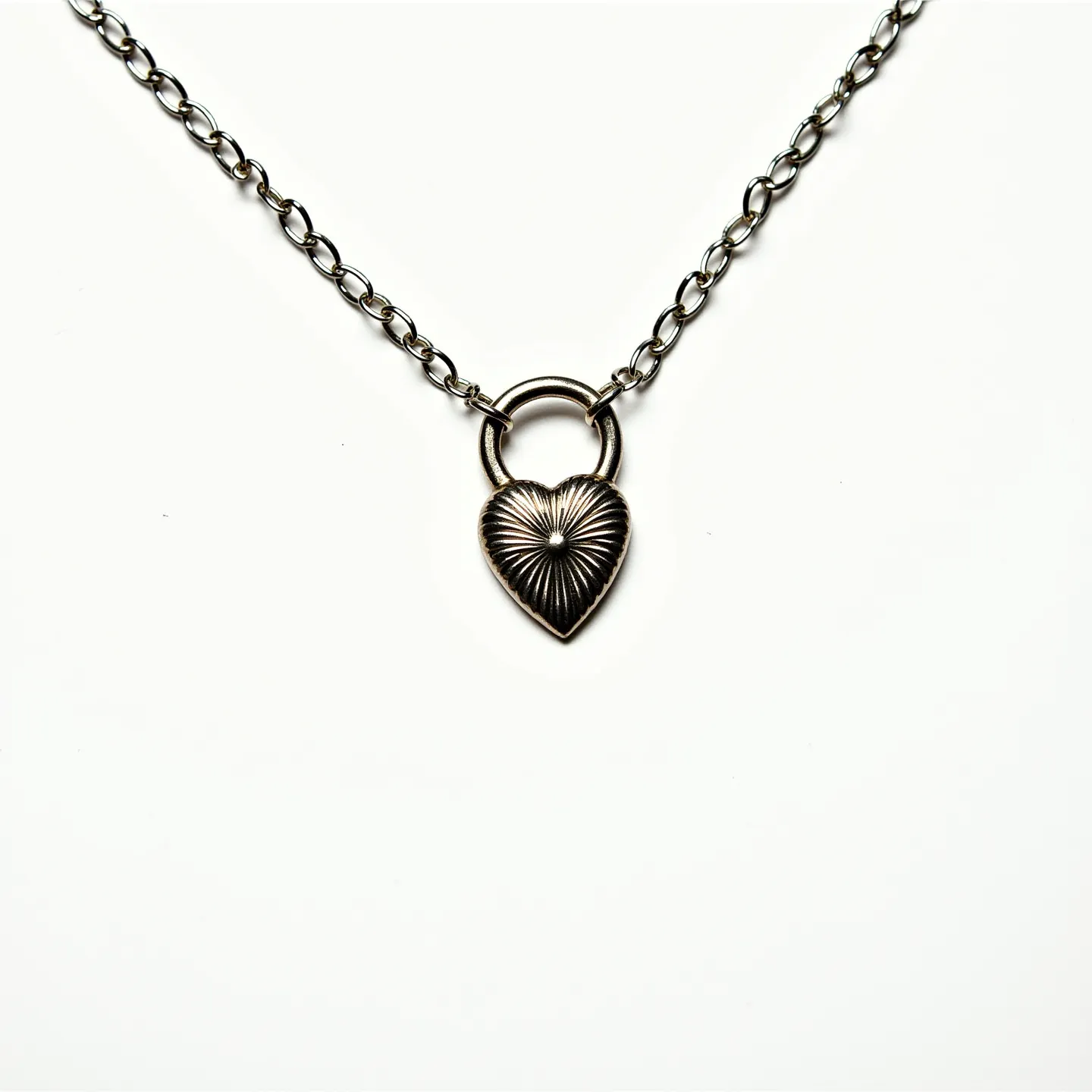 This sacred heart necklace features a pendant with a detailed design resembling a heart with radiating lines, crafted from a metallic material that gives it a timeless appearance. The heart is connected to a loop, enhancing its visual appeal and creating a focal point on the chain. The chain itself consists of interlocking links, likely made of the same metal as the pendant, adding a cohesive aesthetic. The necklace appears to be secured with a straightforward yet sturdy clasp typical of necklaces of this style, ensuring both security and ease of wear.