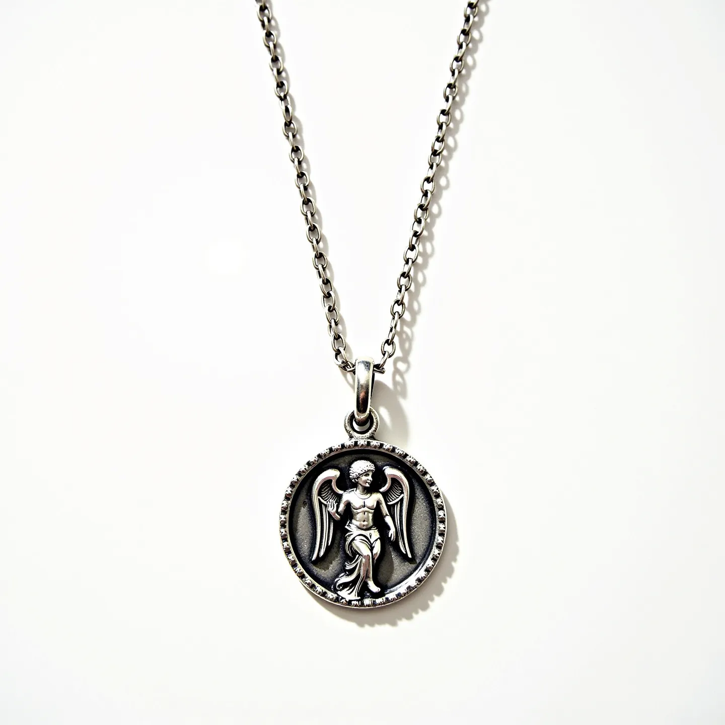 This Saint Michael necklace features a round pendant crafted in a silver-toned metal, showcasing a detailed depiction of Saint Michael. The pendant is attached to a matching silver-toned chain. The chain has interlocking oval links and is connected to the pendant via a simple bail, which allows the pendant to hang freely. The overall design highlights the intricate details of the figure, with emphasis on the wings and drapery, and does not include any additional stones or gems. The necklace completes with a standard clasp to secure it around the neck.