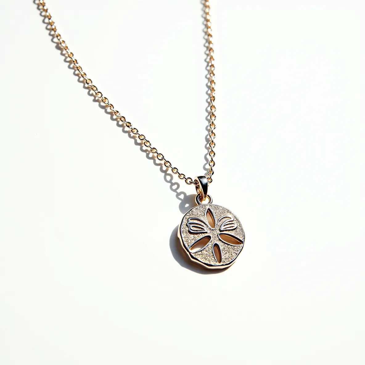 This sand dollar necklace features a delicately crafted pendant, likely made of a shiny metal, with a fine sand dollar design that showcases intricate cutouts resembling the natural patterns of a real sand dollar. The pendant hangs on a dainty chain that complements its elegant appearance. The necklace appears to use a standard loop and clasp closure, providing a secure fastening. Overall, the piece exhibits a harmonious blend of simplicity and detailed artistry, making it a charming accessory.