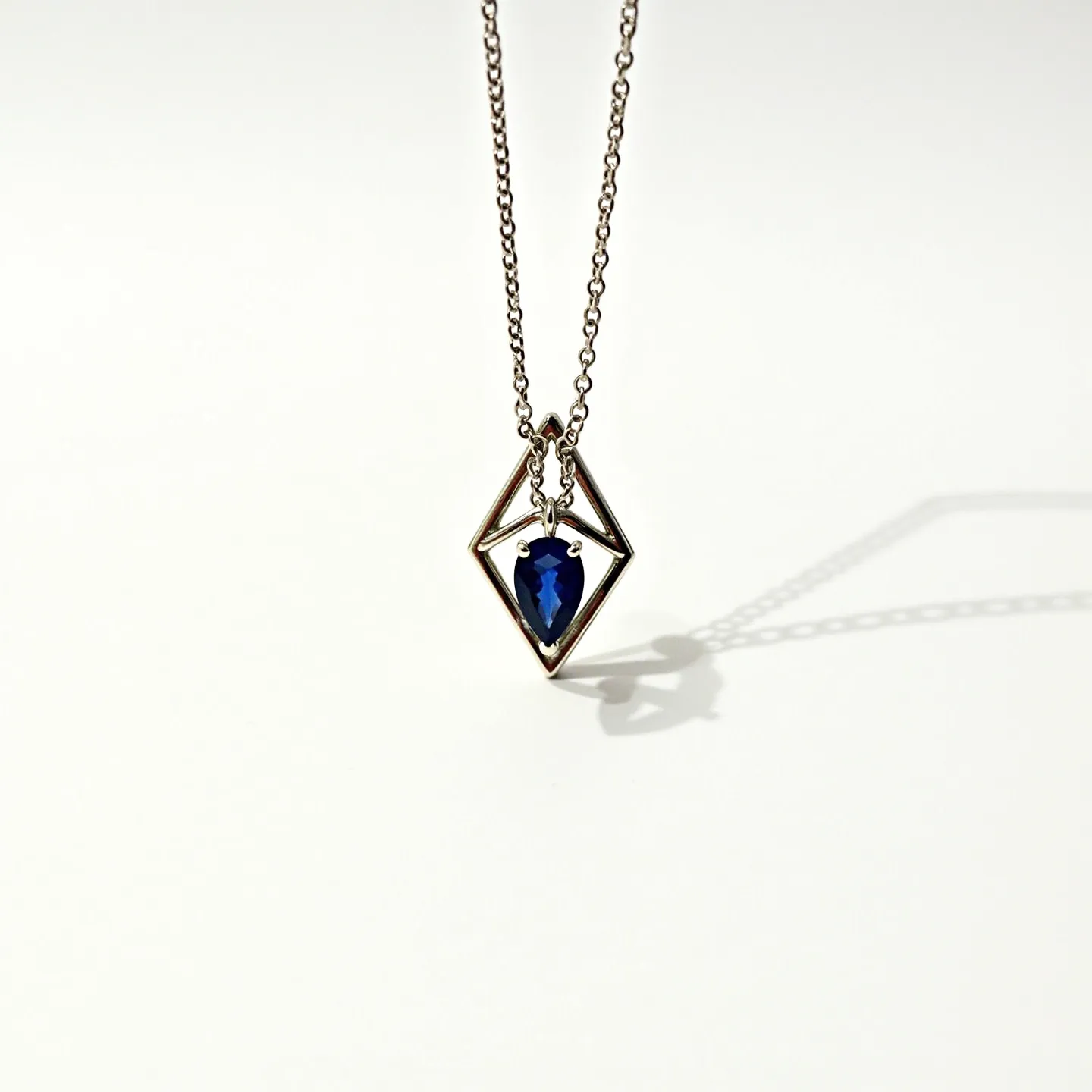 This sapphire necklace features a striking design with a pear-cut sapphire as its centerpiece, set within a geometric silver pendant. The sapphire displays a deep blue hue, enhancing its elegance and complementing the minimalist setting. The pendant is suspended from a delicate silver chain, which adds a refined and contemporary touch. The design incorporates a simple attachment with a chain link clasp, ensuring easy wear and secure closure. The necklace’s modern aesthetics make it a versatile accessory suitable for various occasions.