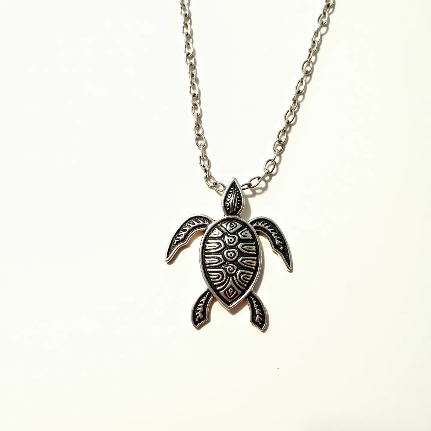 This sea turtle necklace features a pendant intricately crafted in a turtle shape, likely made from a durable metal with a polished silver-tone finish. The pendant's design incorporates detailed patterns that mimic a turtle shell and fins. It is suspended from a medium-link chain that appears to be made of the same or a similar metal, providing a cohesive look. The necklace includes a standard chain clasp, which allows for easy fastening and adjustment. The craftsmanship and thoughtful design elements make it both a stylish and symbolically rich accessory.