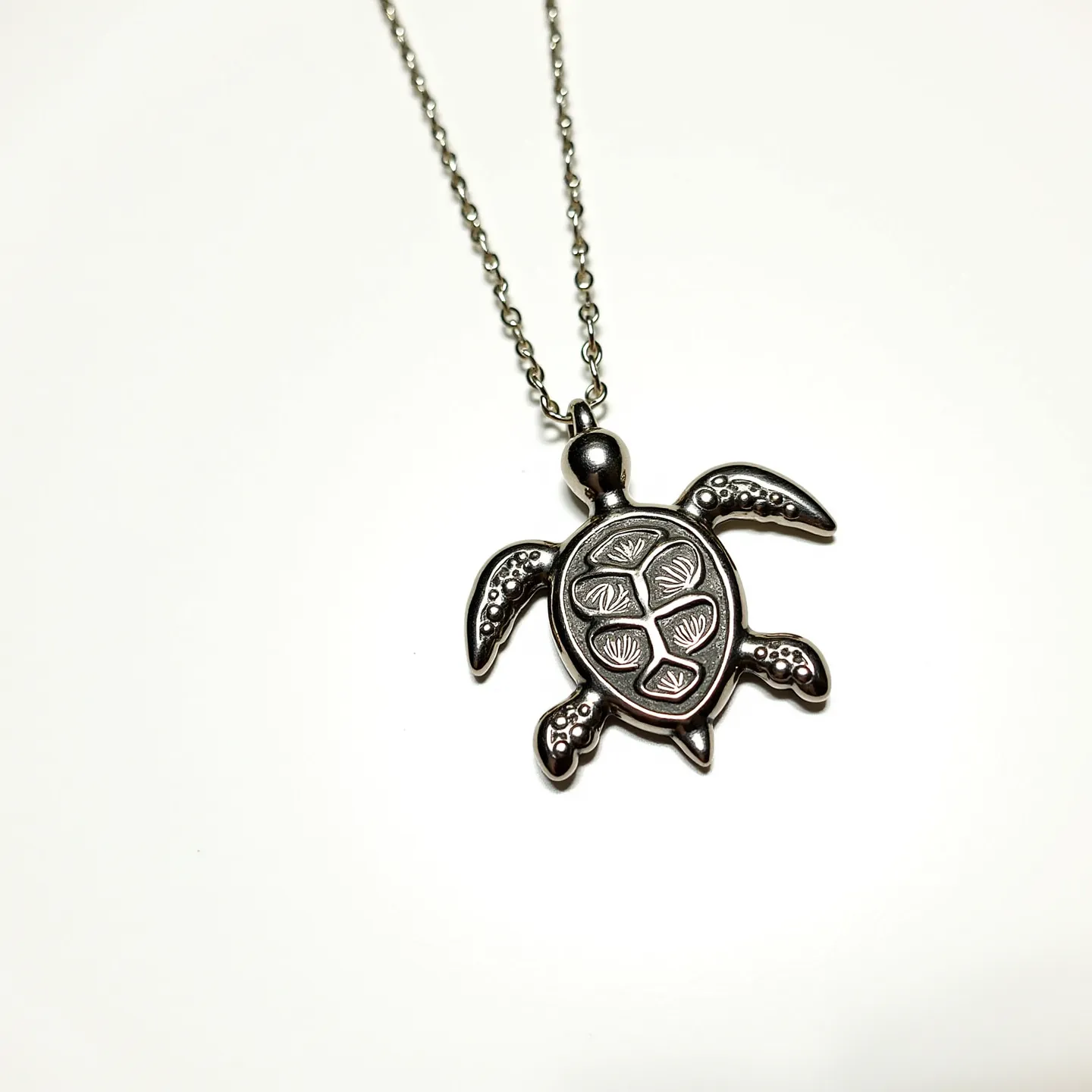 This sea turtle necklace features a detailed pendant crafted from metal with an intricate design on the shell that evokes the natural patterns found on a sea turtle's back. The pendant is attached to a metal chain, which is delicate yet sturdy, suggesting durability and ease of wear. The necklace does not appear to include any gems, focusing instead on the artistic expression of the turtle itself. The chain is likely equipped with a standard clasp for secure fastening. This piece combines simplicity with elegance, making it a versatile accessory for nature enthusiasts and jewelry lovers alike.