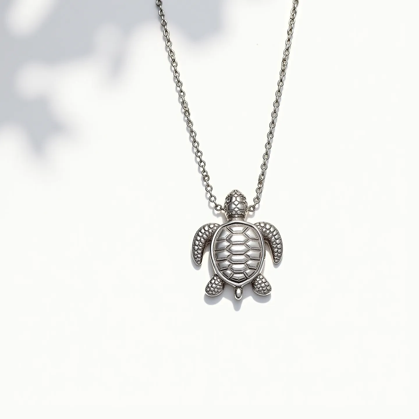 This sea turtle necklace features a pendant crafted in a metallic material, likely silver, given its reflective and polished appearance. The turtle's shell is depicted with intricate detailing, simulating the natural texture of a real sea turtle shell. The flippers and head of the turtle are also intricately designed, enhancing the pendant's realistic look. The necklace is suspended on a chain that appears to be made of the same metallic material, providing a cohesive design. A standard clasp attachment ensures secure wearability. The necklace lacks any visible gemstones, focusing instead on the detailed metallic work.