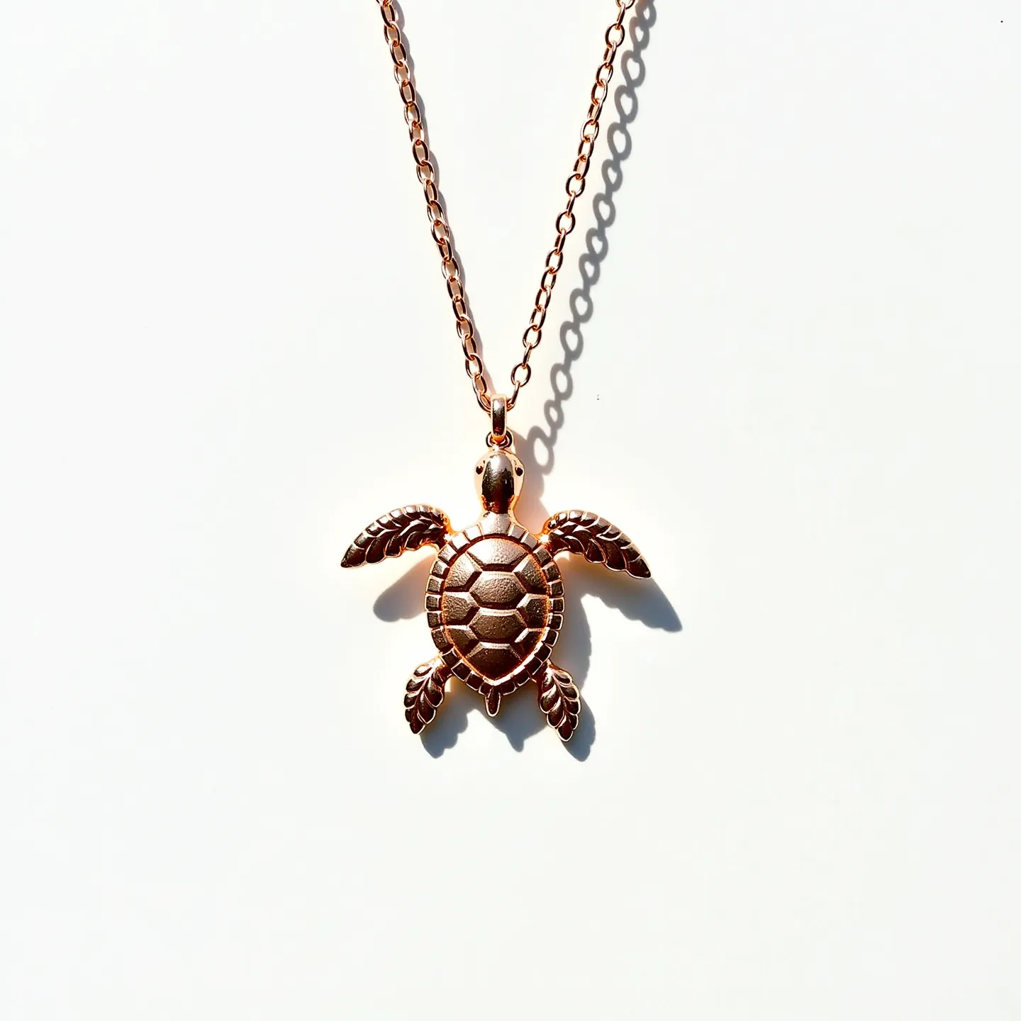 This sea turtle necklace features a finely crafted pendant shaped like a sea turtle, made from a metallic material with a shiny, polished finish, possibly rose gold or copper-plated. The turtle's shell and limbs are detailed, adding texture and depth to the design. The pendant hangs from a delicate chain, which is likely made from the same material as the pendant to maintain visual consistency. The necklace is equipped with a standard lobster clasp, providing secure attachment while allowing for easy wear and removal. The overall design exudes a sense of elegance and simplicity, making it suitable for a variety of occasions.