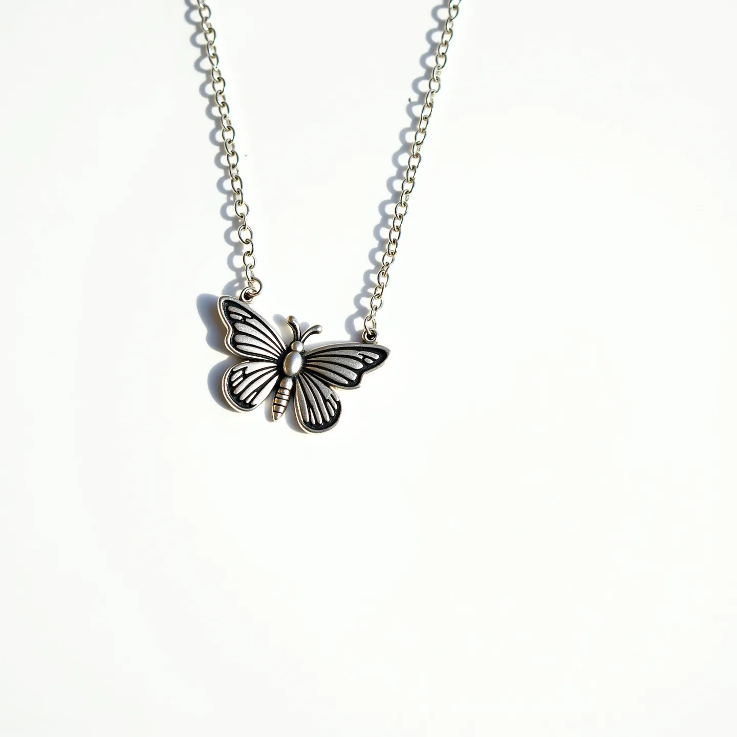 This silver butterfly necklace features a polished butterfly pendant crafted from silver, exhibiting intricate detailing in the wings for a delicate appearance. The chain is composed of linked silver, ensuring a harmonious design with the pendant. There are no visible gems or stones adorning the butterfly, emphasizing its simplicity and elegance. The necklace likely utilizes a standard clasp mechanism for secure attachment, seamlessly integrating with the chain's design to prioritize both function and style.