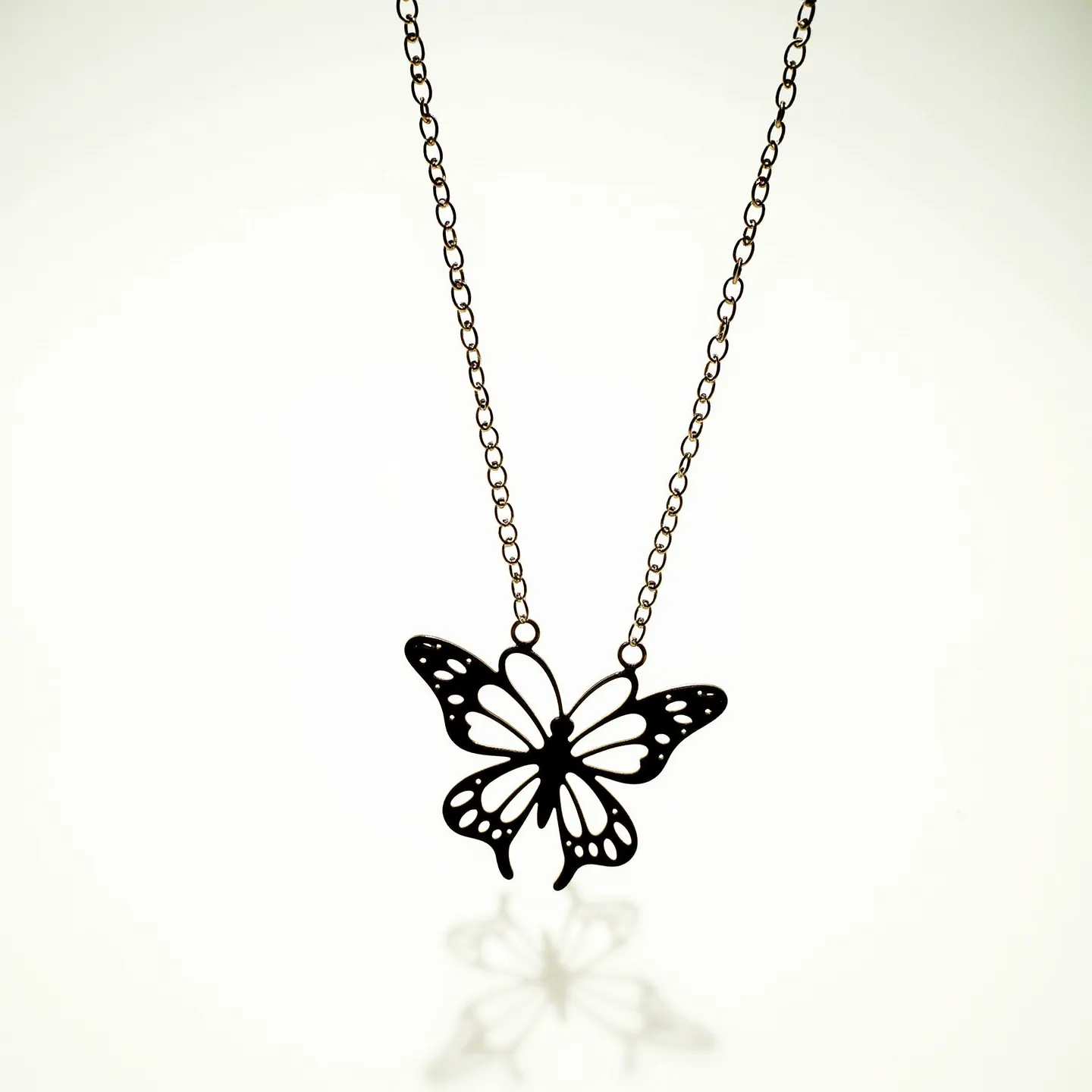 This silver butterfly necklace features an intricately designed pendant shaped like a butterfly, crafted from what appears to be polished silver. The pendant has a cut-out pattern that enhances its delicate appearance. Attached to a simple chain, the pendant connects securely on either side, implying a firm attachment to the chain. The necklace is likely secured with a classic clasp mechanism, although it is not visible in the image. The design emphasizes elegance and simplicity, making it a versatile piece for various occasions.