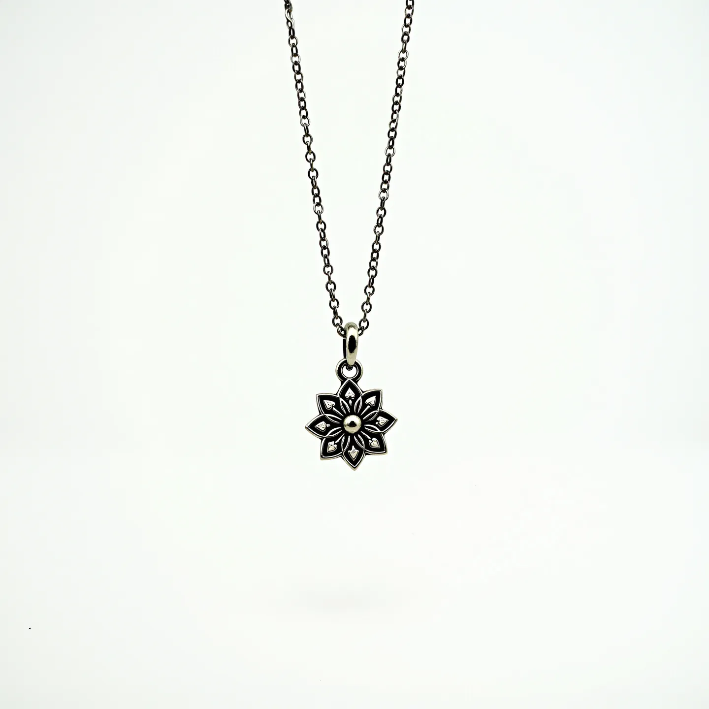 This silver chain features a delicate, interlocking link design, supporting a pendant shaped like a stylized flower. The pendant is intricately crafted with detailed petals, radiating outward from a central point, lending the piece an elegant allure. Each petal displays a symmetrical pattern that enhances its artistic appeal. The chain is likely secured with a classic clasp, ensuring easy wearability. The overall appearance suggests a single-material construction, focusing on the craftsmanship and design of the pendant.