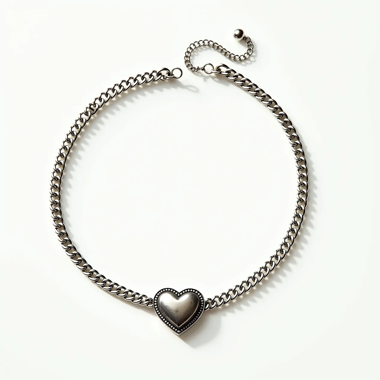 This silver choker necklace features a sturdy chain with a heart-shaped centerpiece, creating a classic and elegant design. The necklace is crafted from polished silver, lending it a sleek, metallic finish that complements the simple yet sophisticated style. The heart is bordered by a subtle beaded edge, adding an extra touch of texture to the piece. It is equipped with an adjustable chain extension and a small spherical clasp, allowing for a customizable fit. The overall design is both timeless and versatile, suitable for a variety of occasions.