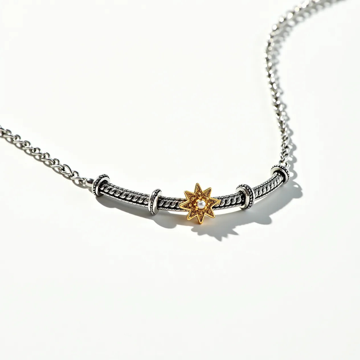 This silver choker necklace features a central decorative element with a gold-toned star design, which is embellished with a small, centrally-placed clear gemstone. The stone appears to be set in the center of the star, providing a focal point with its polished surface. The necklace includes a chain composed of silver links which likely provide both durability and an adjustable fit. The main section of the choker shows a silver rope-like design flanked by several sleek rings. A clasp or other attachment mechanism is present to ensure secure wearability, allowing the necklace to maintain its elegant aesthetic.