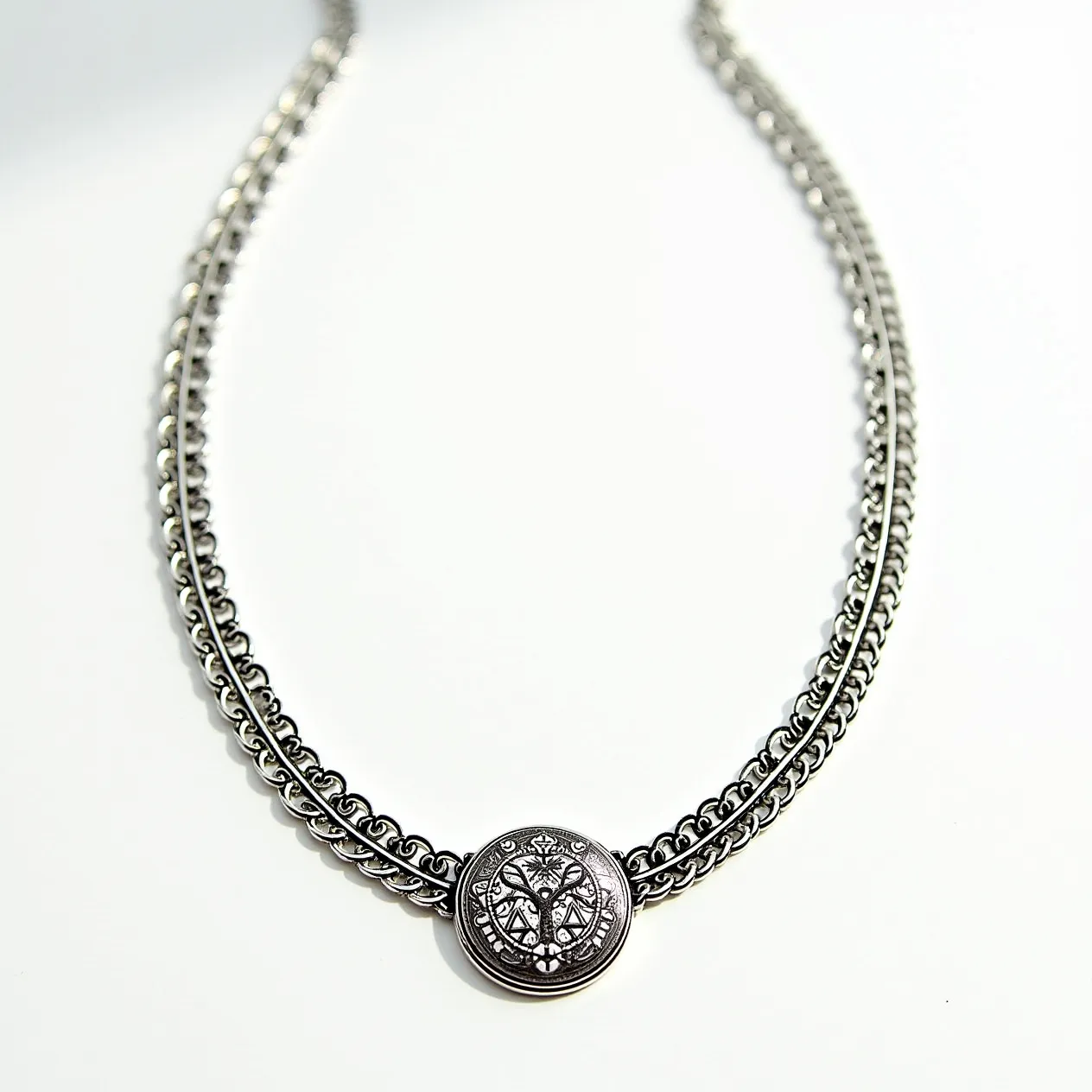 This silver choker necklace is crafted from a dual chain design, featuring intricately linked loops that create a sturdy and elegant structure. At its center is a circular medallion with an embossed design, adding a focal point to the piece. The necklace is constructed entirely of silver, giving it a cohesive, polished appearance. It is secured with a simple clasp mechanism, ensuring it can be worn comfortably around the neck. The intricate chain work and decorative medallion highlight the craftsmanship of the piece.