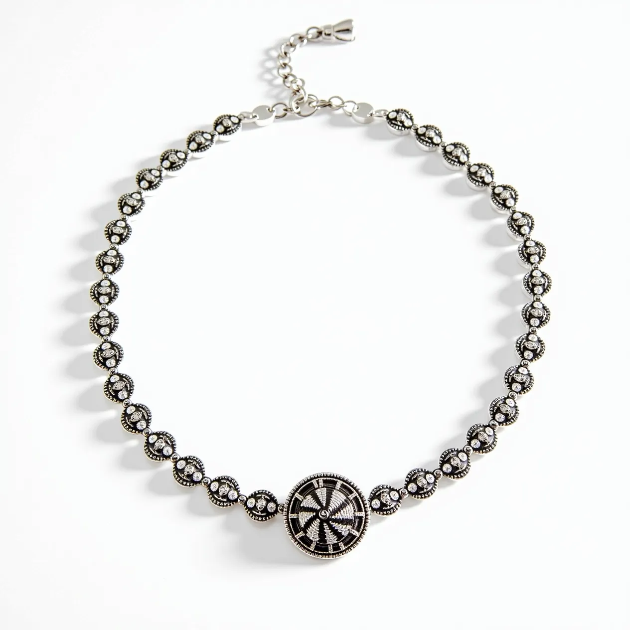 This silver choker necklace features a series of intricate circular motifs, each adorned with what appears to be small, sparkling stones set in a symmetrical pattern. The centerpiece is a larger, ornate circular medallion with detailed embellishments, enhancing the overall design. The necklace likely utilizes cubic zirconia or similar stones, carefully placed in a bezel-like setting to maximize their shine. The choker is equipped with an adjustable chain and a lobster clasp, allowing for flexibility in fit and ease of wear. The overall craftsmanship reflects a blend of elegance and sophistication, making it a striking accessory.