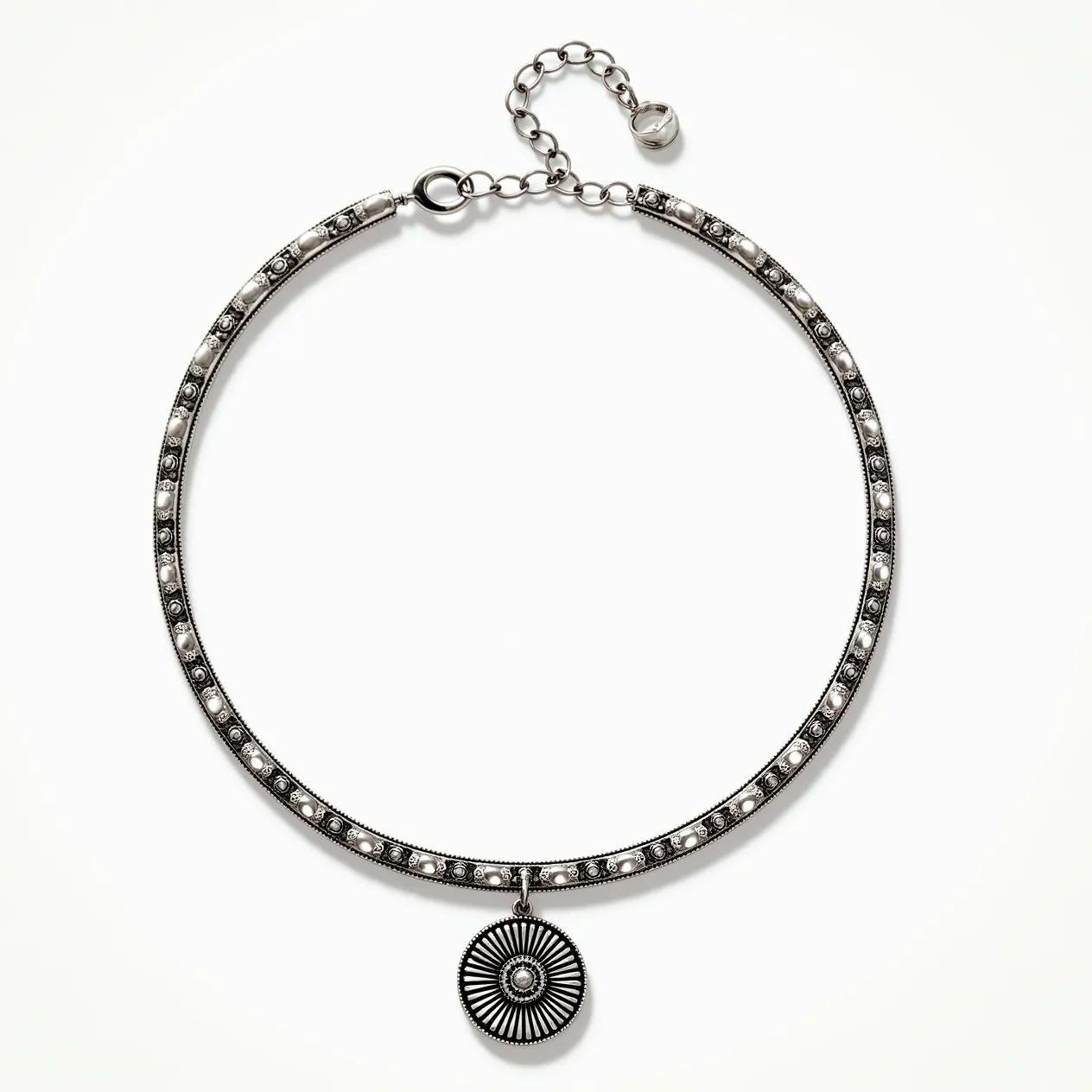 This silver choker necklace features a series of intricately set small circular embellishments along its length, which may include pearls or bead-like stones, providing a textured aesthetic. The choker is adorned with a round pendant that showcases a radiating, engraved pattern, adding a focal point to the piece. The necklace fastens with a lobster clasp connected to an adjustable chain, finished with a small metallic bead, allowing for a customizable fit. The combination of materials and detailed crafting creates a striking and elegant accessory.