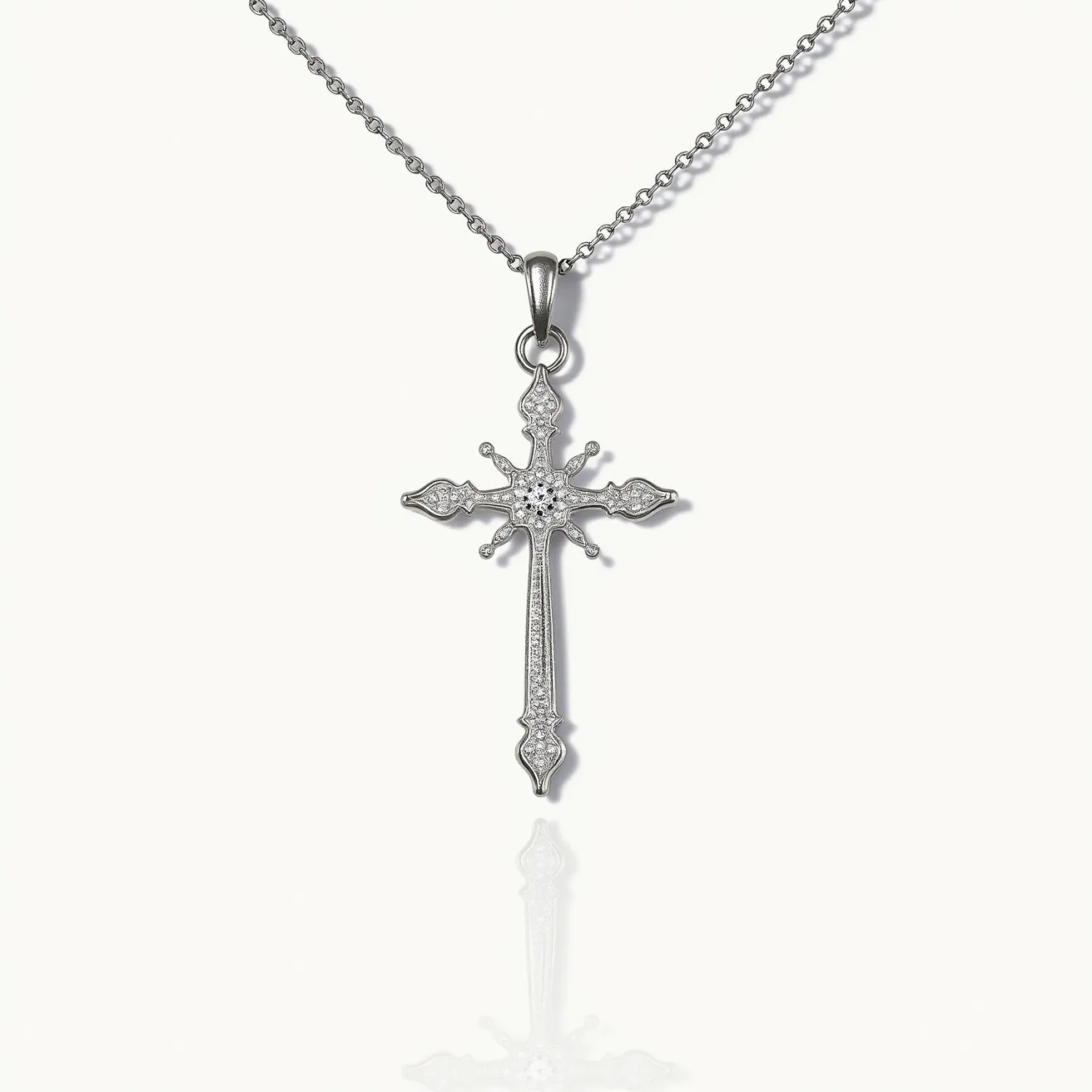 This silver cross necklace features a finely crafted pendant made of sterling silver with ornate detailing. The cross is embellished with small, clear gemstones, likely diamonds or cubic zirconia, beautifully cut and set in a pavé style to accentuate the design's elegance. The pendant hangs from a delicate cable chain, which is likely also made of sterling silver, and is secured with a classic lobster clasp for a secure fit. The combination of the shiny silver and sparkling stones gives the necklace a sophisticated and timeless appeal.