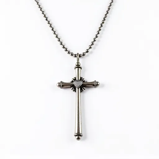 This silver cross necklace features a sleek and polished design with a cylindrical shape that flares out slightly at the ends, adding a modern touch to a classic symbol. At the center of the cross is a small heart motif, which serves as a subtle focal point. The necklace is suspended from a silver ball chain, which complements the cross’s metallic sheen. The clasp is a simple yet secure ball chain connector, ensuring ease of wear while maintaining the overall seamless aesthetic. The entire piece is crafted from silver-toned metal, giving it a timeless and versatile appeal.