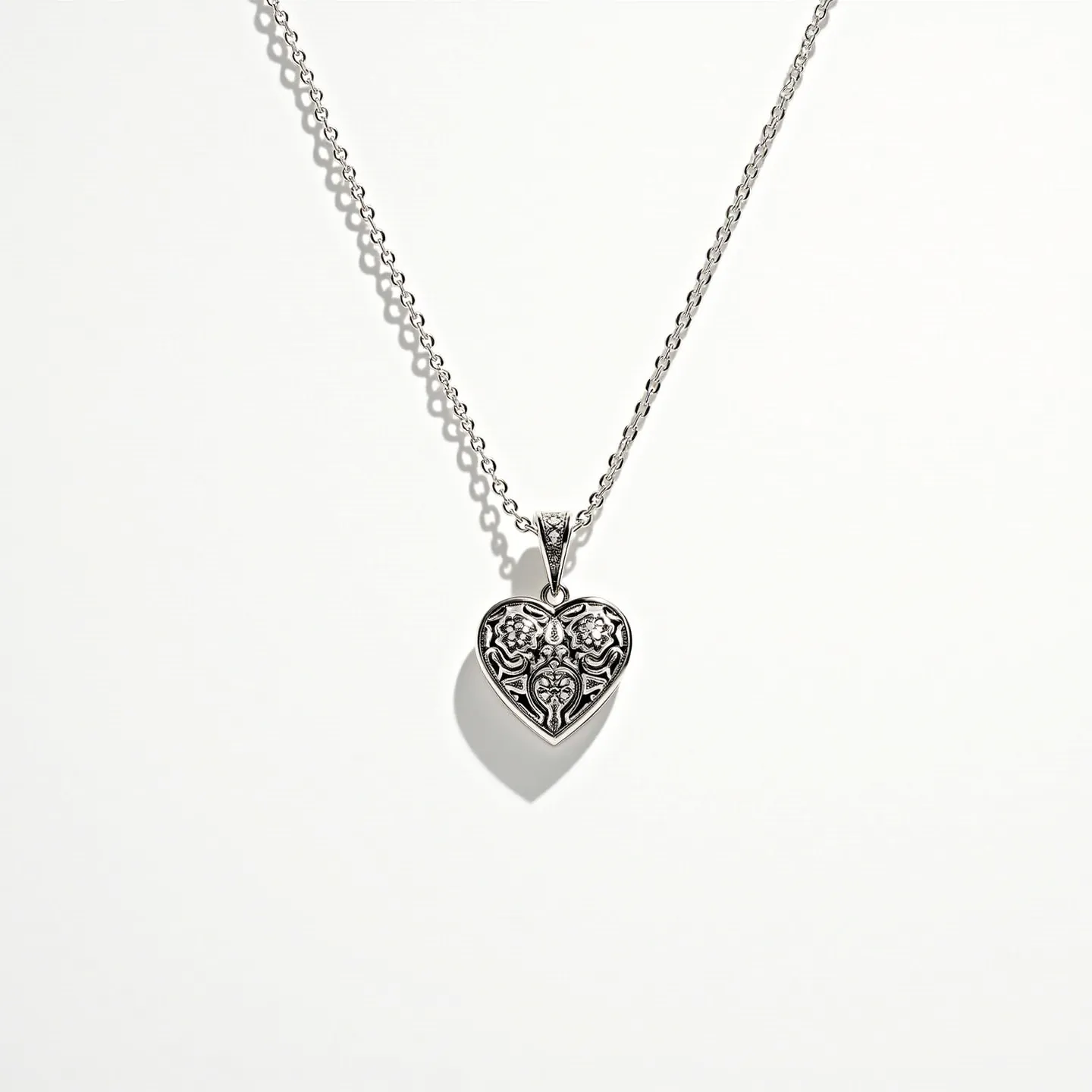 This silver heart necklace features a delicately crafted heart-shaped pendant made from silver, showcasing intricate filigree detailing that adds an elegant touch. The design exudes a vintage charm through its elaborate patterns. The chain is composed of small, interconnected silver links that create a sleek and polished appearance. The necklace is likely secured with a classic lobster clasp, ensuring a secure and adjustable fit. The pendant hangs from a silver bail, allowing for graceful movement and enhancing the overall sophistication of the necklace.