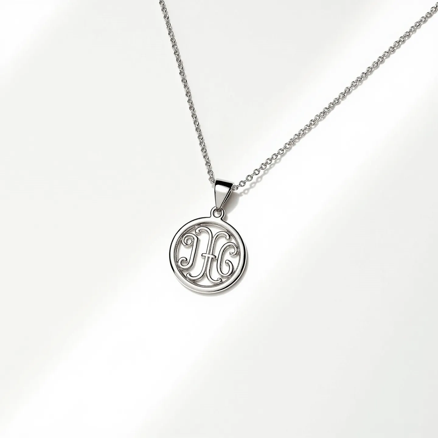 This silver initial necklace features a circular pendant crafted from polished silver, showcasing a decorative initial "H" centrally designed in an elegant, script-like font. The pendant hangs from a delicate silver chain that enhances its refined appearance. It is attached via a simple yet secure loop bail designed to complement the pendant's style without overpowering it. The chain likely uses a spring ring or lobster clasp, commonly found in such necklaces, to provide both ease of use and reliability.