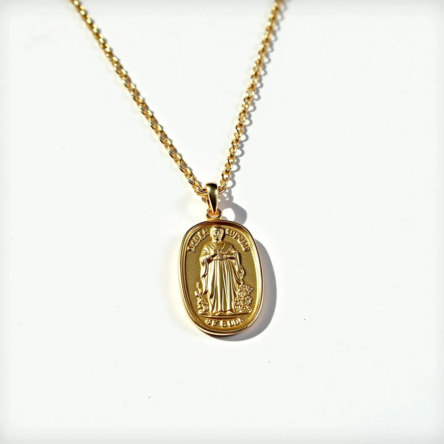 This St. Jude necklace features an intricately crafted gold pendant with a depiction of St. Jude Thaddeus in relief. The design is set on an oval-shaped medallion with detailed inscriptions running along its edges, capturing a classic and reverent appearance. The pendant hangs from a finely linked gold chain that is both simple and elegant in design, likely made from gold or a gold-plated metal. The chain is secured with a small, subtle clasp which allows for easy fastening. The overall craftsmanship exhibits a polished, lustrous finish, highlighting the necklace’s refined and timeless aesthetic.