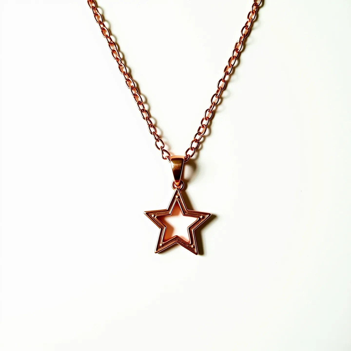 This star necklace features a polished metal star-shaped pendant, likely crafted from a copper or rose gold-toned material, creating a warm and elegant appearance. The star pendant is suspended from a matching chain composed of interlinked loops, which contributes to its durability and aesthetic charm. The pendant hangs from a simple loop bail, seamlessly connecting the pendant to the chain, which is likely fastened with a traditional clasp mechanism, ensuring secure wear. The clean design and shiny finish highlight the necklace's simplicity and intricate craftsmanship.