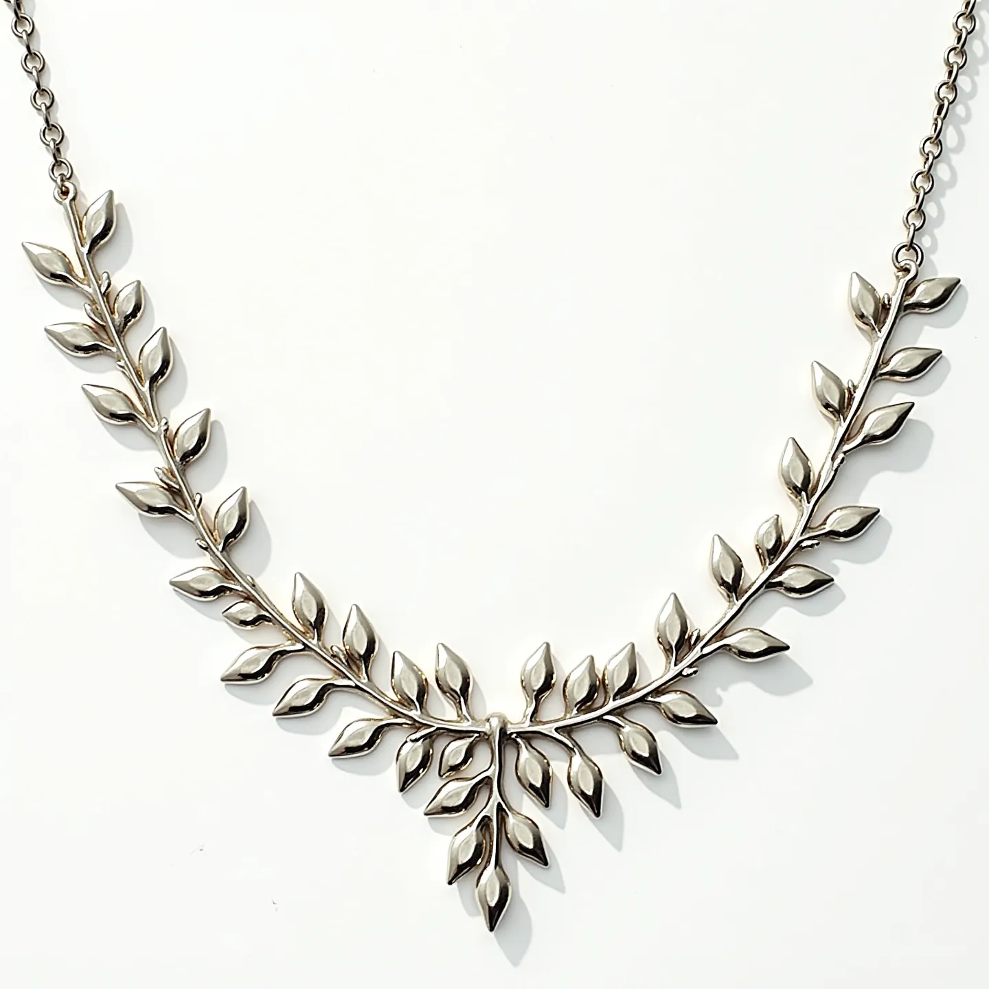 This sterling silver necklace features an intricate leaf motif design, with numerous polished leaves connected to form a harmonious and elegant drape. The leaves are crafted from sterling silver, contributing to a bright, reflective quality. The necklace consists of segments connected in a flowing arrangement, evoking a natural, organic aesthetic. It is likely secured with a chain link clasp that ensures a secure and comfortable fit. The craftsmanship highlights a smooth and continuous metalwork finish without the presence of any gemstones, emphasizing the refined silverwork.