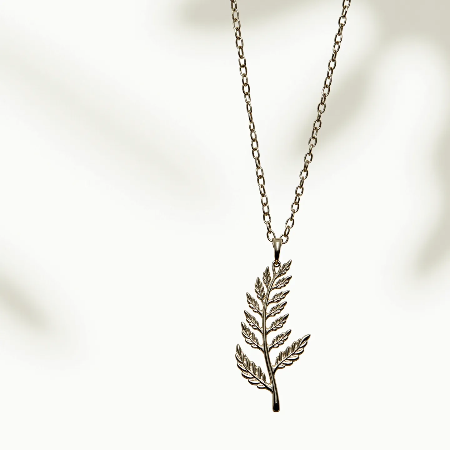 This sterling silver necklace features a delicate, intricately crafted fern leaf pendant, which captures an elegant and nature-inspired design. The pendant hangs from a smoothly polished silver chain, composed of evenly-sized links that provide a classic and timeless appearance. The chain connects with a secure spring ring clasp, ensuring ease of wear and reliability. The pendant's design highlights the detailed veins and contours of the leaf, making it a charming piece of jewelry that embraces the beauty of the natural world.