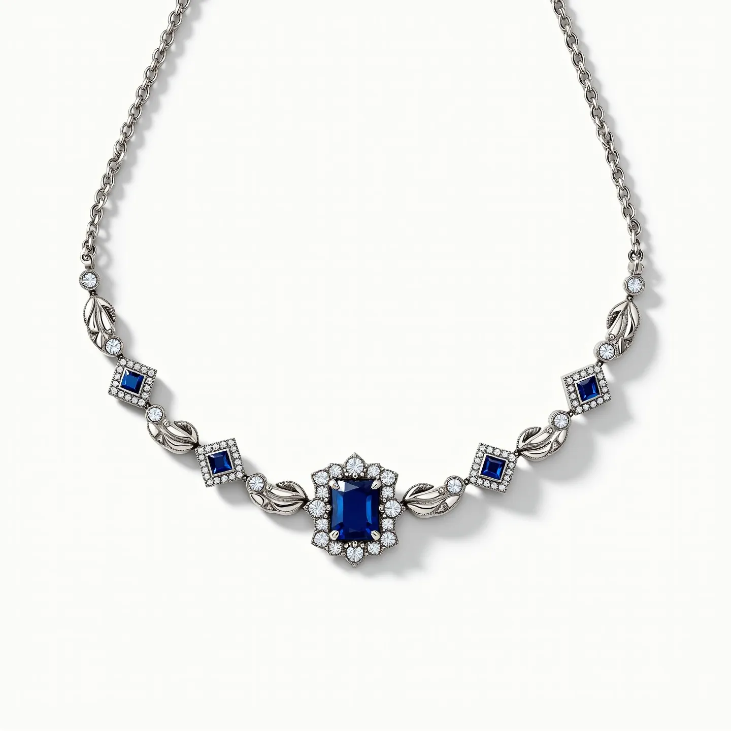 This stone necklace features a stunning central deep blue stone, possibly a sapphire, which is emerald-cut and surrounded by a halo of small clear stones that accentuate its brilliance. The surrounding design includes a sequence of smaller, square-cut blue stones, each set in a square bezel settings and interspersed with decorative silver elements resembling leaves or petals interlaced with clear stones. The metal appears to be a polished silver or white gold, adding a sleek and complementary backdrop to the vibrant blue stones. The necklace is connected by a delicate chain, and it is likely secured with a clasp that ensures both elegance and functionality.