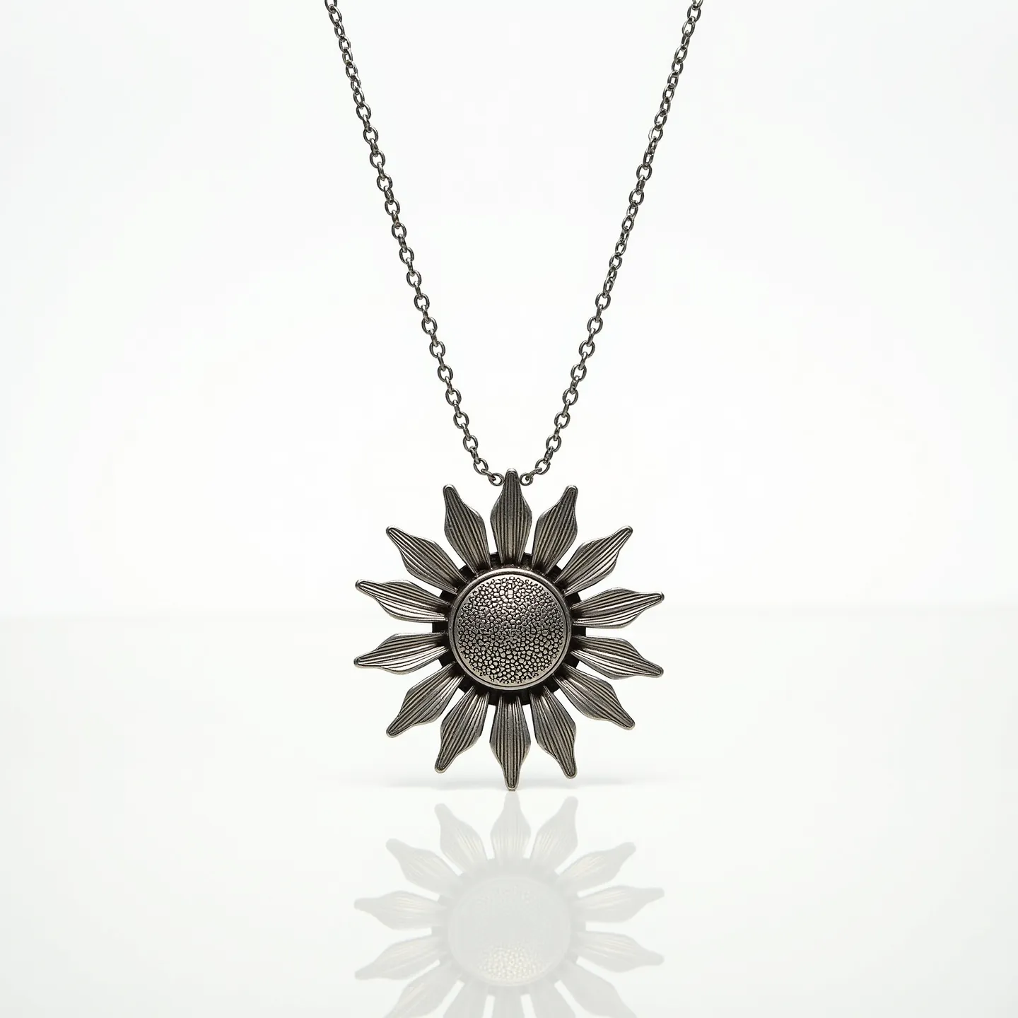 This sunflower necklace features a intricately designed pendant that mimics the detailed appearance of a sunflower, exhibiting a textured central disc surrounded by stylized petals. The necklace is crafted from a metallic material, lending it a polished and uniform look. The central disc is embedded with a textured pattern, adding visual interest to the piece, though it does not contain any gemstones. The pendant is suspended from a delicate chain that appears sturdy and is complemented by a simple clasp, likely providing both security and ease of wear.