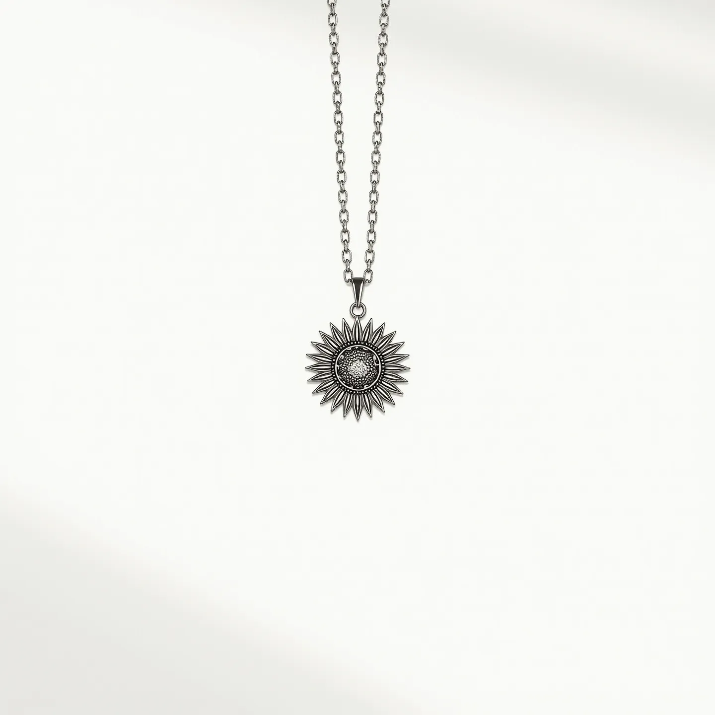 This sunflower necklace features a detailed sunflower charm crafted from a silver-toned metal, which adds a classic and elegant touch to the piece. The pendant showcases intricate petal designs with a textured center that catches light, enhancing the sunflower's natural appearance. The necklace is composed of a matching metal chain with evenly sized links, contributing to its consistent and polished look. A small loop attaches the pendant to the chain, ensuring stability and ease of movement. The necklace is completed with a lobster clasp, offering a secure and convenient fastening mechanism.