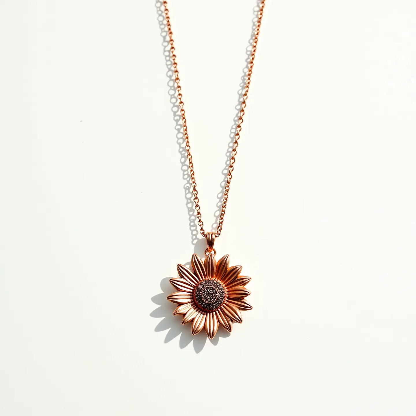 This sunflower necklace features a detailed sunflower pendant crafted from a shiny metal with a warm, golden hue, possibly resembling gold or gold plating. The pendant is attached to a fine link chain, matching the golden tone of the sunflower. The center of the sunflower is textured, providing a contrast to the smooth and polished petals surrounding it. There is no presence of gems or stones, and the necklace is most likely fastened with a standard clasp, although not visible here. The craftsmanship highlights the delicate design of a sunflower, combining elegance with a touch of nature-inspired beauty.