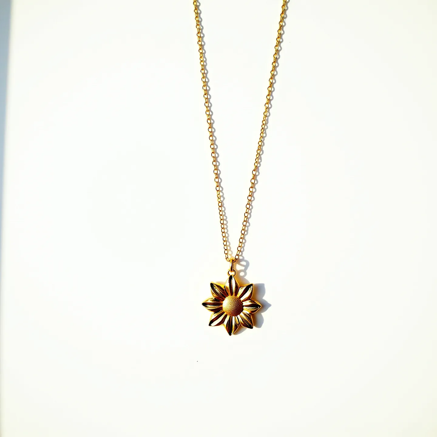 This sunflower necklace features a delicate chain composed of small, evenly-spaced links that create an elegant silhouette. The pendant is crafted in the shape of a sunflower, with intricate detailing on the petals and a textured center, capturing the natural beauty of the flower. The pendant appears to be made from a metal with a warm, golden hue, possibly gold-plated or brass, which enhances its appeal. The necklace is likely secured with a simple clasp, possibly a lobster claw, providing both functionality and ease of wearing. This piece combines artisanal craftsmanship with a nature-inspired design.