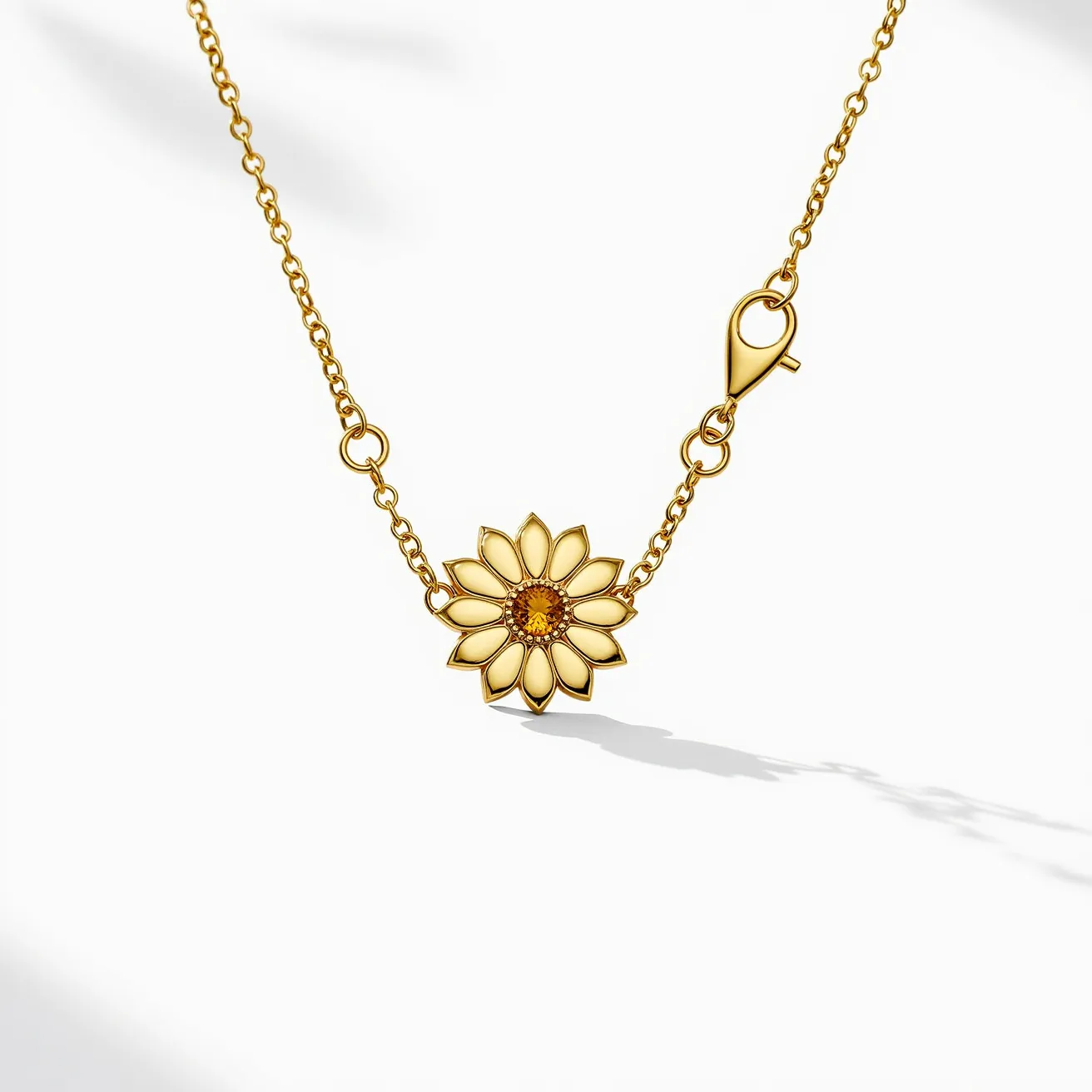 This sunflower necklace features a charming sunflower pendant crafted from a gold-tone metal, with petals delicately outlined to highlight their shape and detail. At the center, an amber-colored gem is set, possibly a citrine or a similar stone, which is faceted to capture and reflect light, creating a vibrant focal point. The chain is composed of fine links, complementing the pendant with a harmonious aesthetic. For secure wear, the necklace is equipped with a lobster clasp, ensuring functionality and easy attachment.