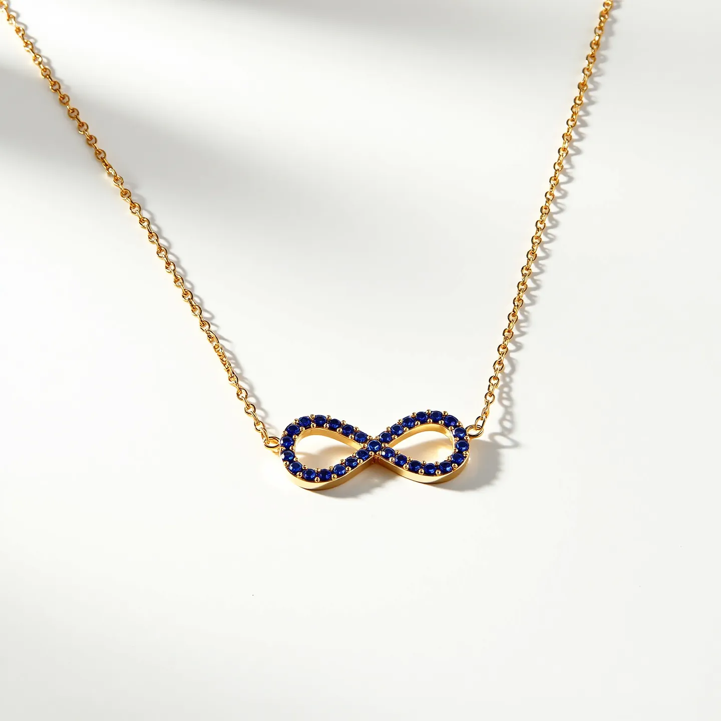 This tanzanite necklace features an elegant infinity symbol pendant encrusted with small, round-cut tanzanite stones, beautifully set in a gold setting that accentuates the deep blue color of the gems. The pendant is seamlessly attached to a delicate gold chain, which complements the overall aesthetic and adds a touch of sophistication. The necklace is likely secured with a standard clasp, ensuring both style and security for the wearer. The blend of gold and tanzanite creates a striking contrast, making it a versatile piece suitable for various occasions.