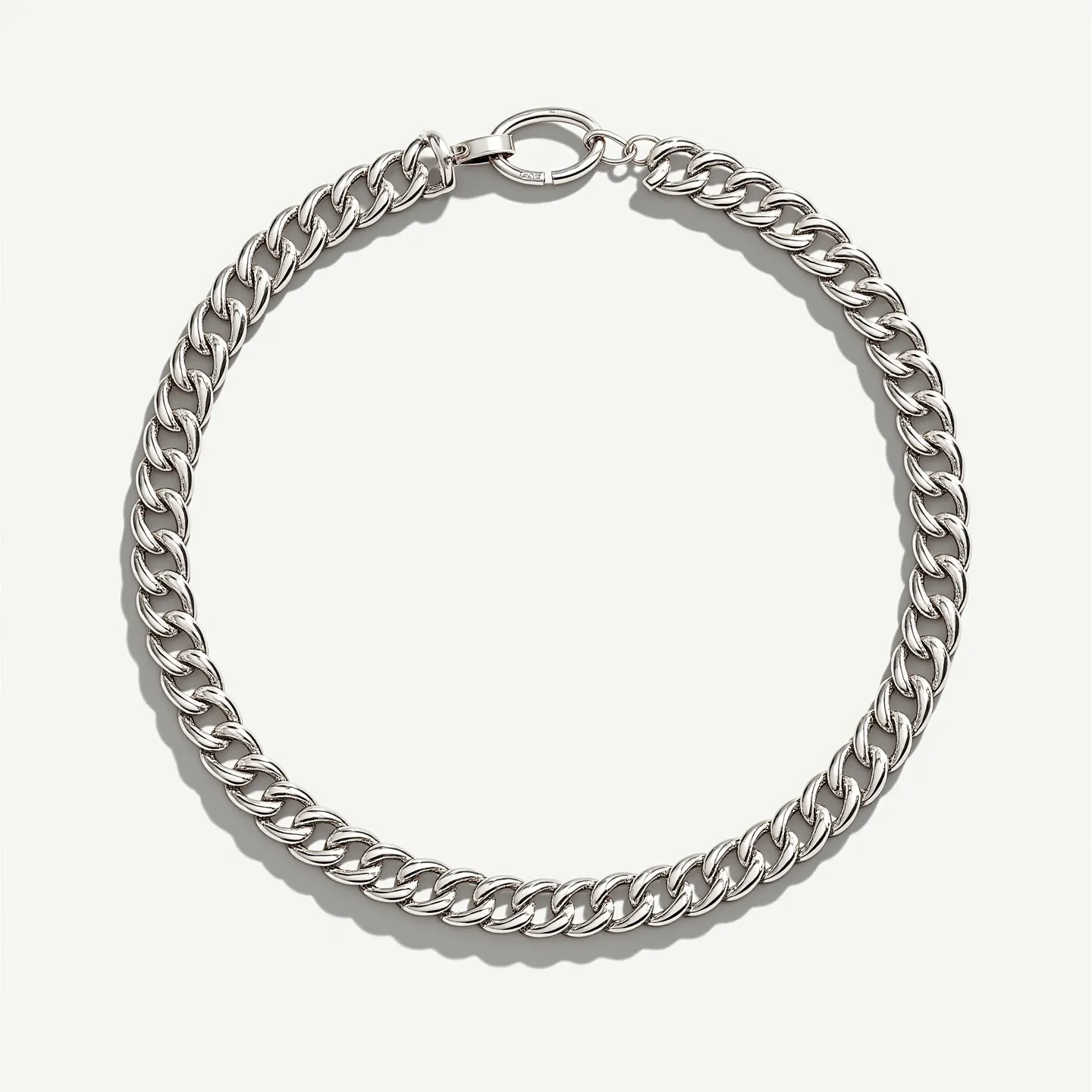 This thick chain necklace is crafted from a polished metal, possibly stainless steel or sterling silver, giving it a sleek and modern appearance. It features a curb chain design, characterized by flat, interlocking links that provide a smooth, uniform look. The necklace is secured with a large, sturdy round clasp, which provides both functionality and a touch of style. There are no visible gems or stones, emphasizing the bold impact of the chain itself. The design is versatile, suitable for both casual and formal wear.