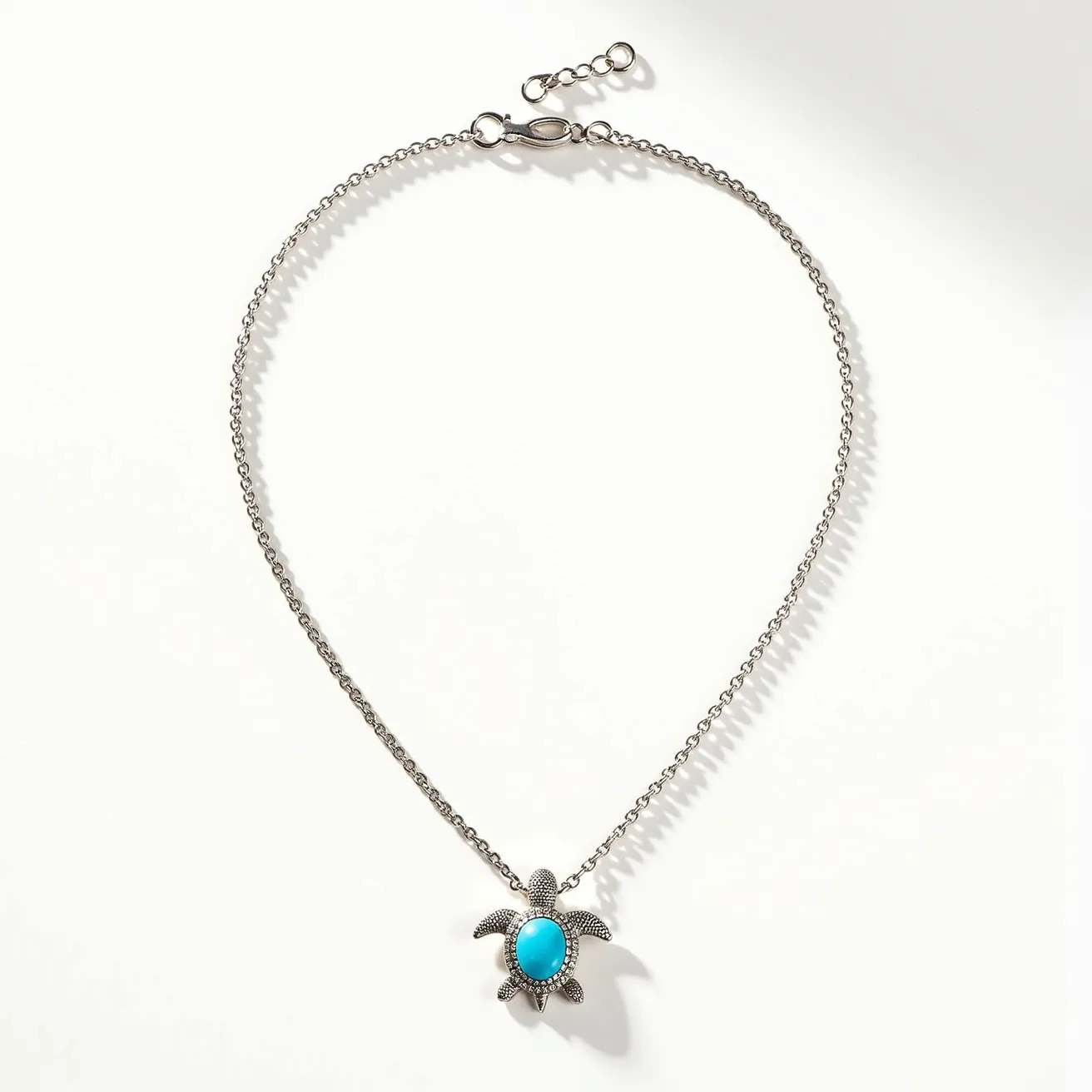 This turtle necklace features a delicate metal chain with an adjustable clasp for length versatility. The pendant is shaped like a turtle and is adorned with a vibrant turquoise stone at its center, which is oval-cut and securely bezel-set. The turtle's body is detailed with small, clear stones, likely mimicking a pavé setting, enhancing the overall sparkle and design. The combination of the turquoise and the shimmering stones gives the piece an elegant yet charming appearance.