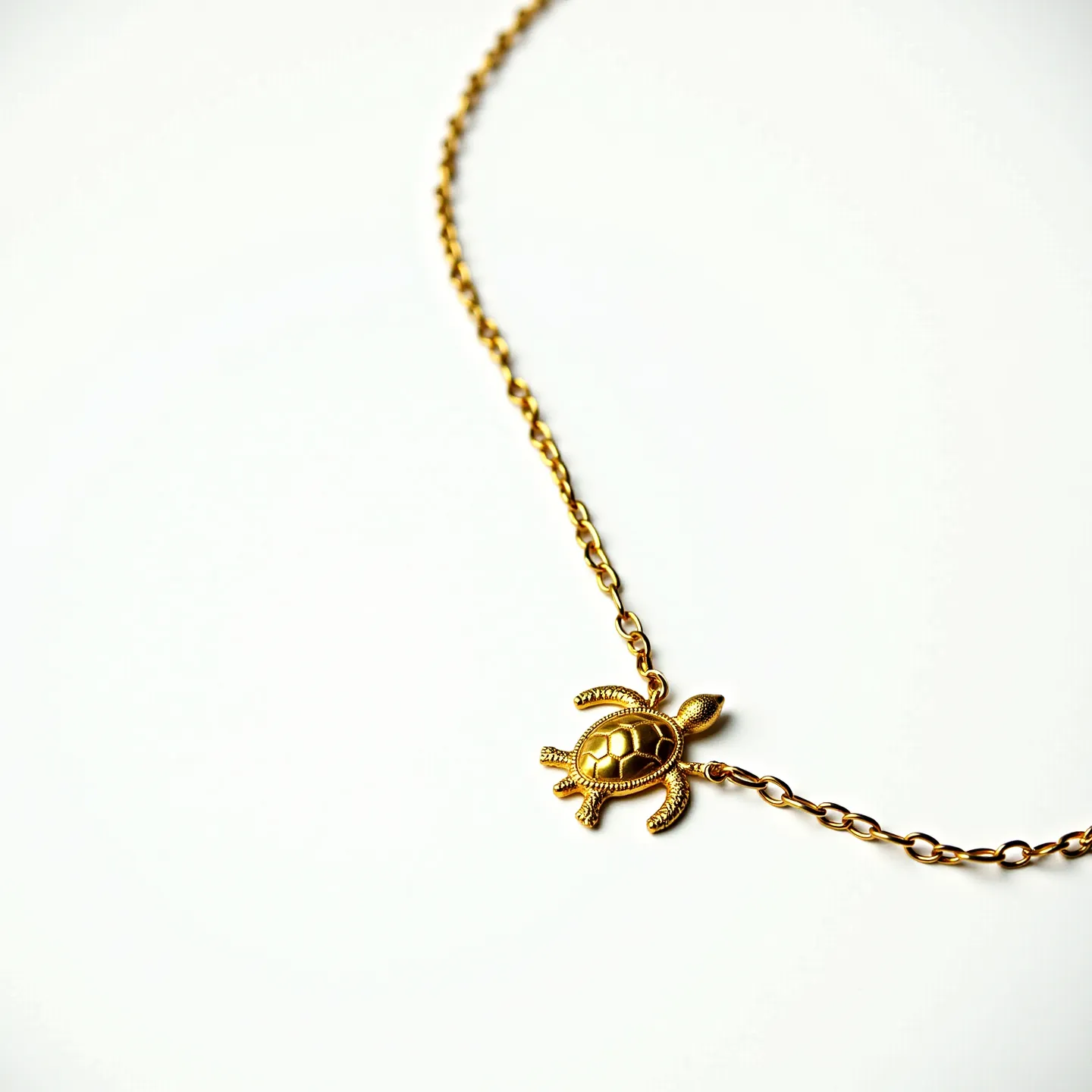 This turtle necklace features a beautifully crafted turtle pendant made of gold-toned metal, offering a smooth and polished appearance. The chain is composed of matching metal links, consistent in style with the pendant, providing a cohesive design. The turtle displays intricate detailing, particularly on the shell, which adds to its charm and allure. The necklace is fastened with a simple clasp that complements the overall aesthetic, ensuring a secure fit while maintaining elegance. The absence of additional gems or stones keeps the focus on the turtle design, making it an understated yet eye-catching piece of jewelry.