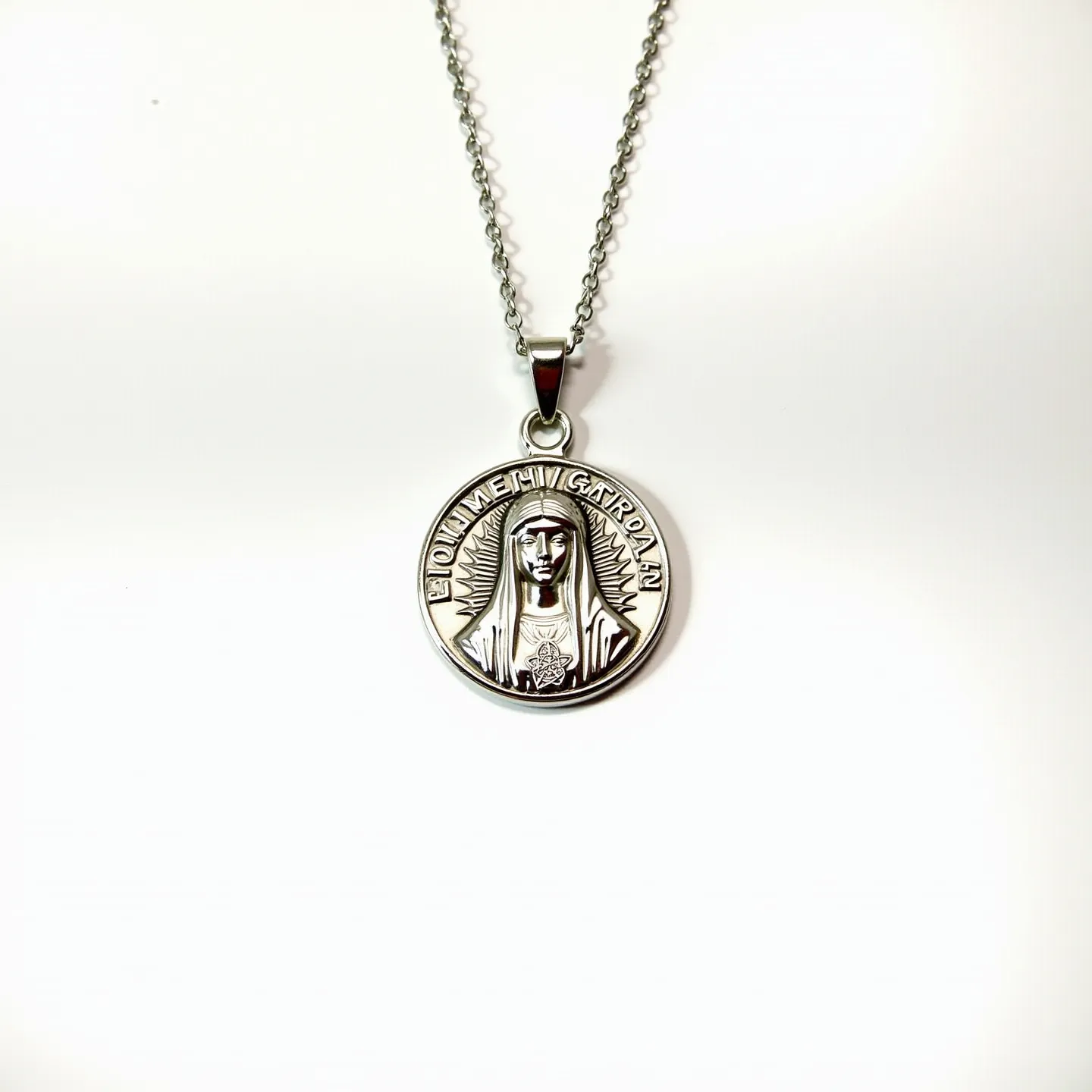 This Virgin Mary necklace features a pendant crafted from a silver-toned metal, depicting an intricately engraved image of the Virgin Mary surrounded by a halo of rays and inscribed with text. The pendant hangs from a classic link chain, also in a matching silver-tone, adding elegance to its design. The chain appears to include a standard clasp, allowing for secure and convenient attachment. There are no visible gemstones or embellishments, emphasizing the detailed craftsmanship of the metalwork in both the pendant and chain.