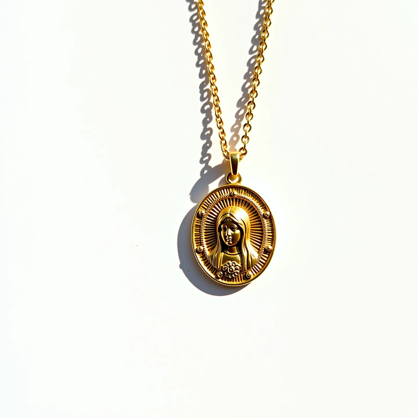 This Virgin Mary necklace features an intricately designed gold-toned medallion showcasing a relief of the Virgin Mary, framed within a polished oval setting. The pendant is suspended from a finely crafted gold-toned chain, accentuating its religious significance. The medallion is detailed with rays emanating from the center, emphasizing the figure of Mary, and small, rounded embellishments that add a subtle touch of elegance. The chain appears to be a classic link style, providing both strength and aesthetic appeal, and is secured with a standard lobster clasp, ensuring ease of wear and reliability.