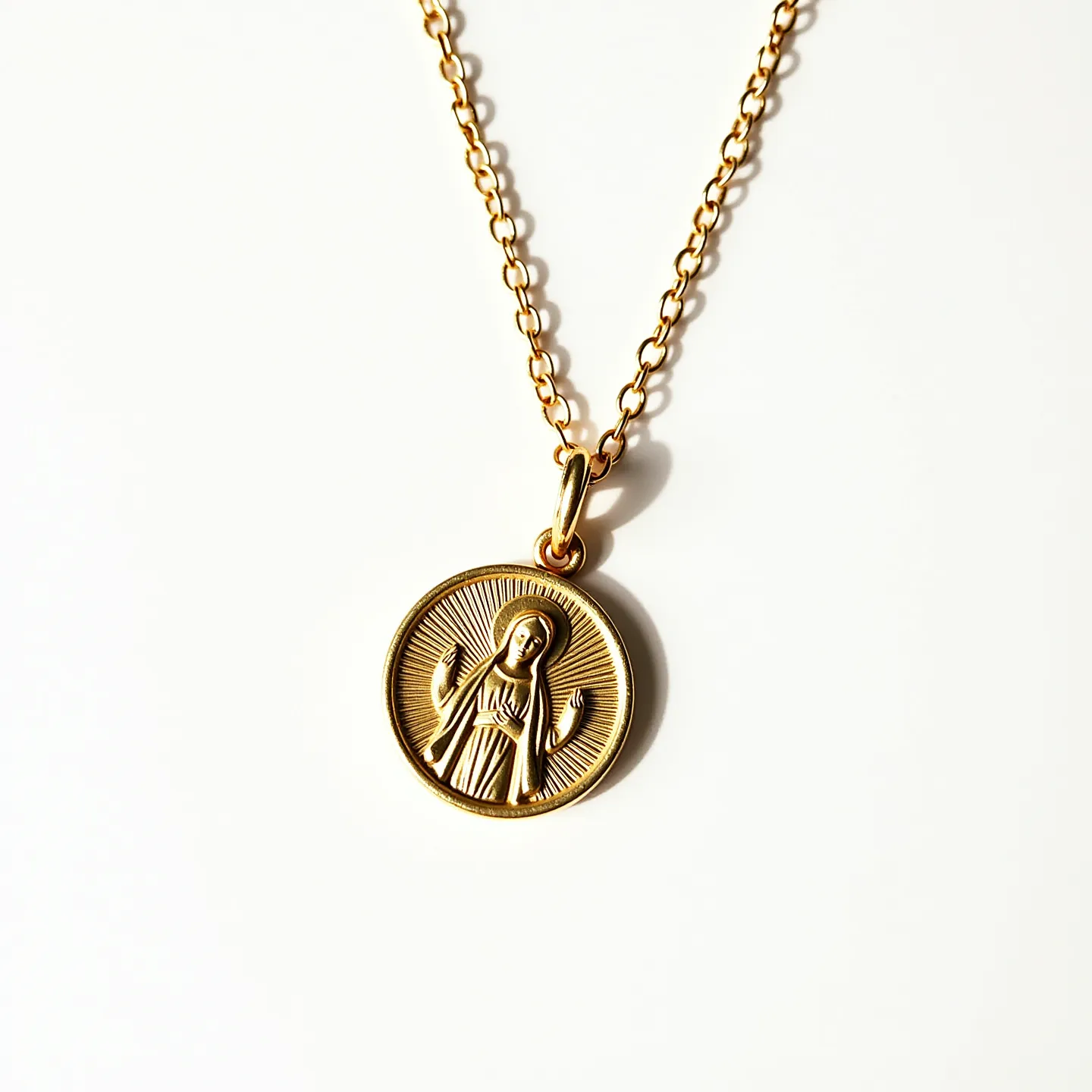 This Virgin Mary necklace features a circular pendant made of what appears to be gold or gold-tone metal, intricately embossed with the image of the Virgin Mary. The pendant is attached to a chain with interlocking links, suggesting a sturdy and classic design. The surface of the pendant showcases a radiant halo effect around the Virgin Mary's figure, enhancing its spiritual symbolism. There are no visible gemstones or additional embellishments on the pendant, keeping the focus on the central image. The necklace includes a simple, elegant bail allowing it to hang freely from the chain, which likely features a standard clasp for closure.