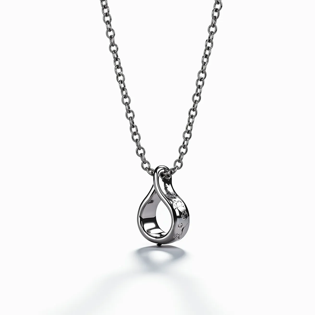 This white gold chain features a simple yet elegant design crafted from interlocking links. It holds a unique pendant, which appears to be a white gold loop with an artistic twist in its form. The pendant may have subtle engraved or embossed patterns, adding a touch of intricate detailing. The chain is likely equipped with a secure clasp to ensure it stays in place when worn. There are no visible gems set into either the chain or the pendant, emphasizing the polished finish and craftsmanship of the white gold material.