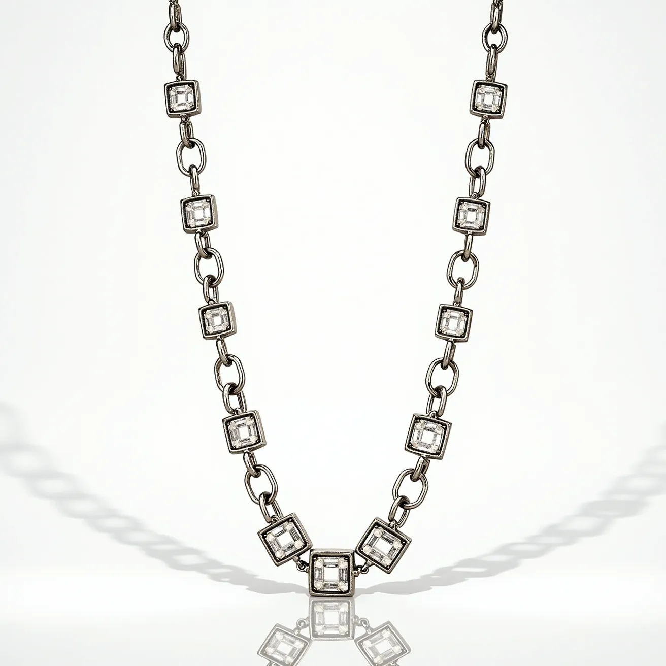 This white gold chain features a series of square settings, each housing a clear gemstone cut into a square shape, likely a princess or step cut. The stones are set within sturdy bezel settings, giving a modern and sleek look. The chain links between the settings are oval-shaped, providing a balanced aesthetic that complements the geometric design of the gemstones. Each stone catches light with precision, adding an elegant sparkle to the overall piece. The chain is likely completed with a secure clasp to ensure ease of wear and a seamless appearance.