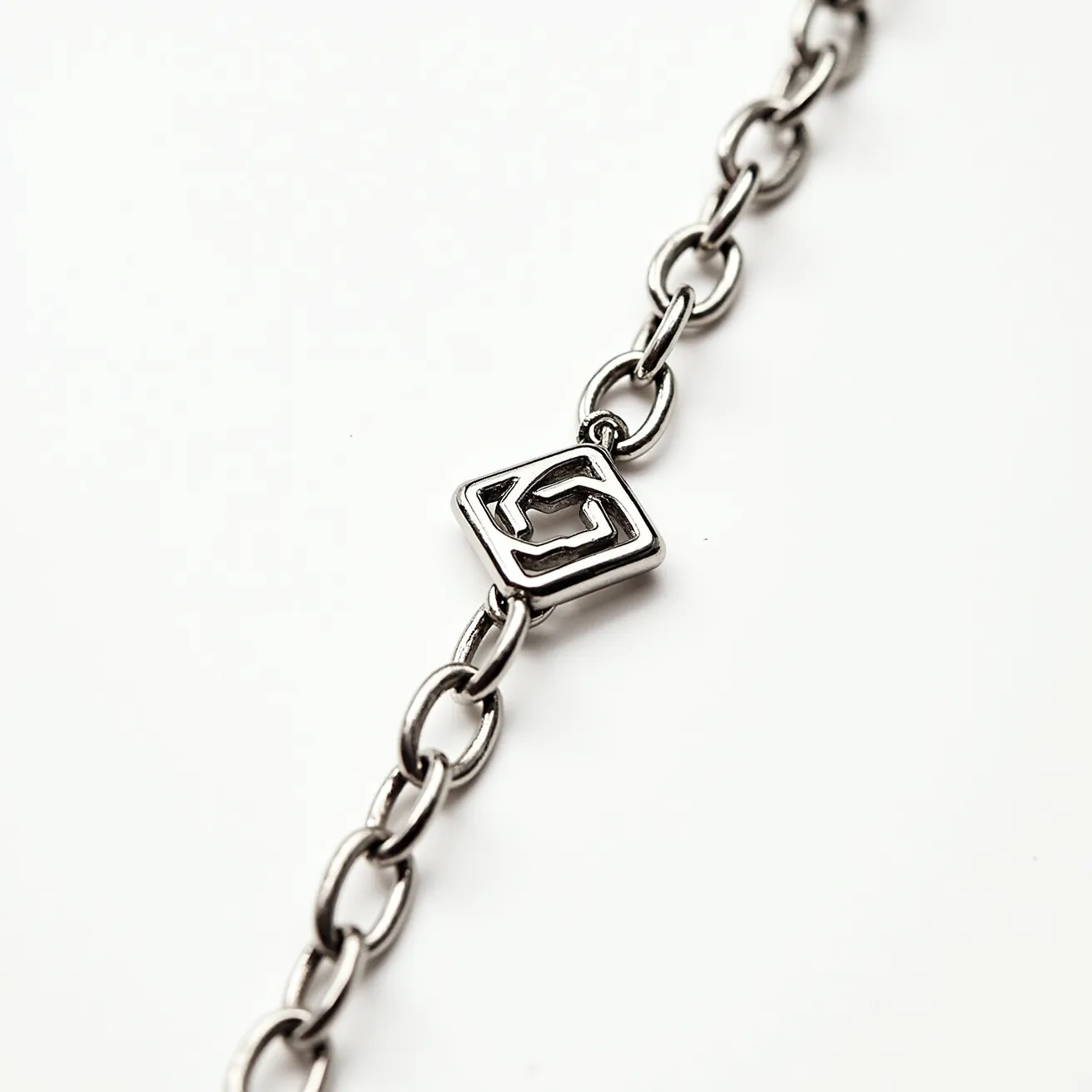 This white gold chain features a series of interlinked oval links, showcasing a sleek and polished finish that enhances its luxurious appearance. At the center of the chain is a square-shaped decorative element that adds a touch of geometric interest and modern style. The chain design is simple yet elegant, relying on the refined sheen of the white gold to provide its allure. The links are smoothly finished, indicating quality craftsmanship, and the overall design suggests versatility, suitable for both casual and formal wear.