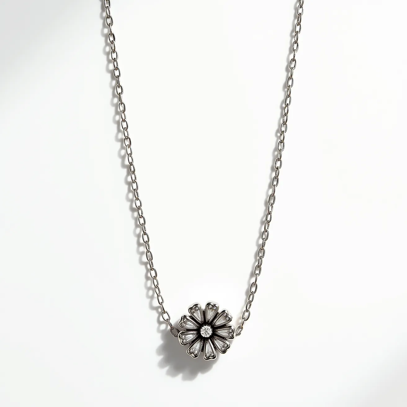 This white gold necklace features a delicate chain that supports a floral pendant design. At the center of the flower is a round-cut gemstone, possibly a diamond, which adds a touch of sparkle to the piece. The necklace includes an intricately designed flower with petal-like shapes surrounding the central stone, showcasing fine craftsmanship. The chain is likely attached with a standard clasp, ensuring secure wear while maintaining the elegance of the entire piece.