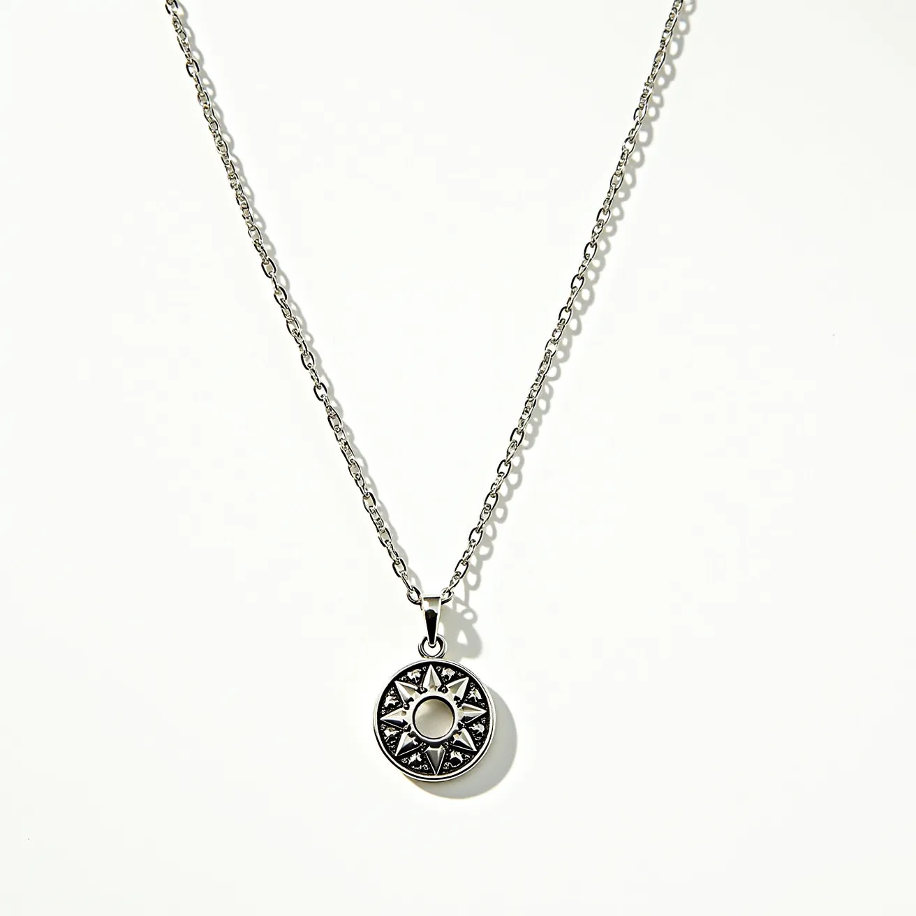 This white gold necklace features a delicate chain that holds a round pendant with an intricate design. The pendant appears to be adorned with gemstones set in a starburst pattern, surrounding a central circular element, possibly a larger gem or design focal point. The gemstones are secured in a bezel setting, which adds to the necklace’s elegant appearance. The necklace closes with a spring ring clasp, ensuring a secure fit. The white gold material enhances the necklace's refined and modern aesthetic, making it a versatile accessory.