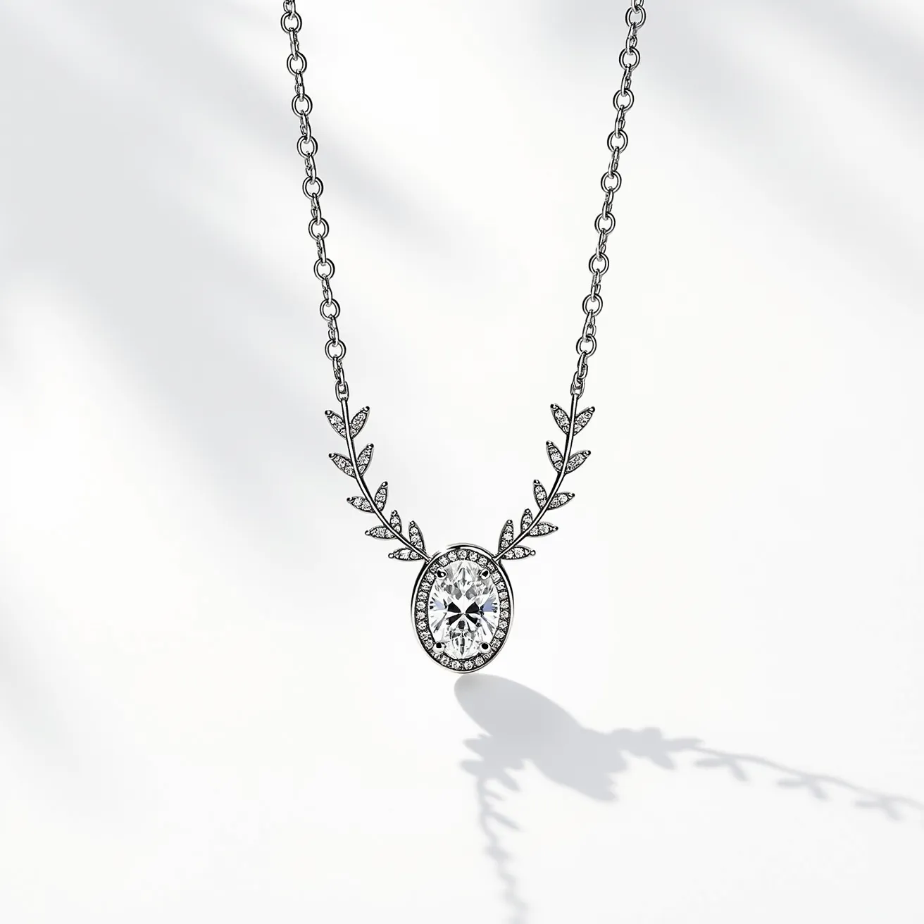 This white sapphire necklace features a beautifully cut white sapphire gemstone set in an elegant oval shape. The center stone is encircled by a halo of smaller clear stones, enhancing its brilliance and highlighting its clarity. The setting is designed to incorporate intricate, decorative elements resembling leaves, adding a delicate and sophisticated touch. These elements are paved with small, sparkling stones that complement the centerpiece. Crafted in a metal that appears to be sterling silver, it includes a simple yet secure chain link that supports the pendant. The clasp is likely a lobster or spring ring, commonly used in fine jewelry for its reliability and ease of use.