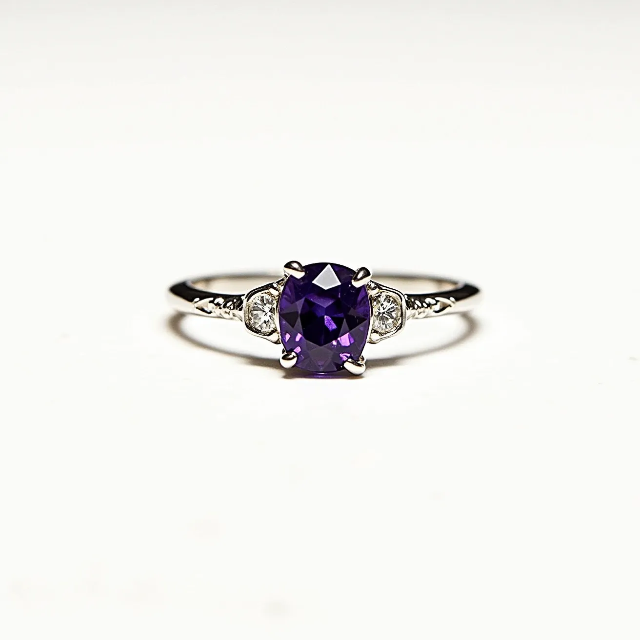 This alexandrite ring features a captivating oval-cut central stone, known for its color-changing properties, showcasing a purple hue. The central gem is elegantly set in a four-prong setting, providing both security and prominence. Flanking the alexandrite are two smaller round diamonds, set in a delicate, possibly white gold or platinum, band that adds additional sparkle and grace. The band itself appears slender, highlighting the intricate details and ensuring the gemstones remain the focal point. This exquisite arrangement makes the ring both sophisticated and timeless.