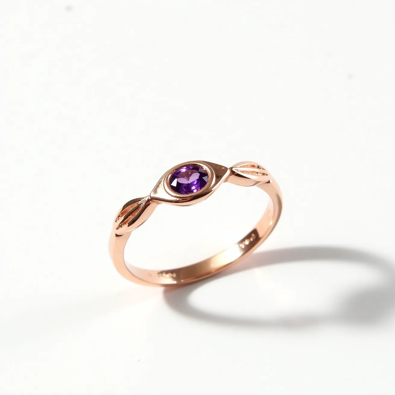 This amethyst promise ring features a beautifully set oval-cut amethyst stone, known for its rich purple hue. The gemstone is securely held in a bezel setting, offering both elegance and protection to the amethyst. Crafted from rose gold, the band enhances the overall allure of the piece, providing a warm, complementary contrast to the vibrant stone. The band also showcases a gentle, twisting design that adds a touch of sophistication and visual interest.