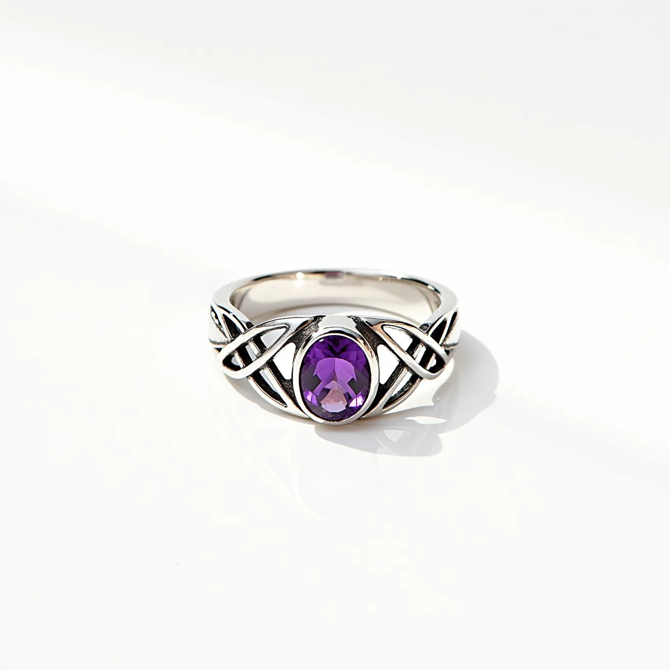 This amethyst promise ring features a centrally set, oval-cut amethyst gemstone, radiating a rich purple hue. The gem is elegantly held in place by a sterling silver band, which showcases an intricate Celtic knot design, adding both symbolism and visual interest to the piece. The craftsmanship highlights the sheen of the silver, enhancing the vibrancy of the amethyst. The ring's setting securely cradles the stone, ensuring both stability and prominence. The overall design is a harmonious blend of elegance and tradition, making it a meaningful promise ring choice.