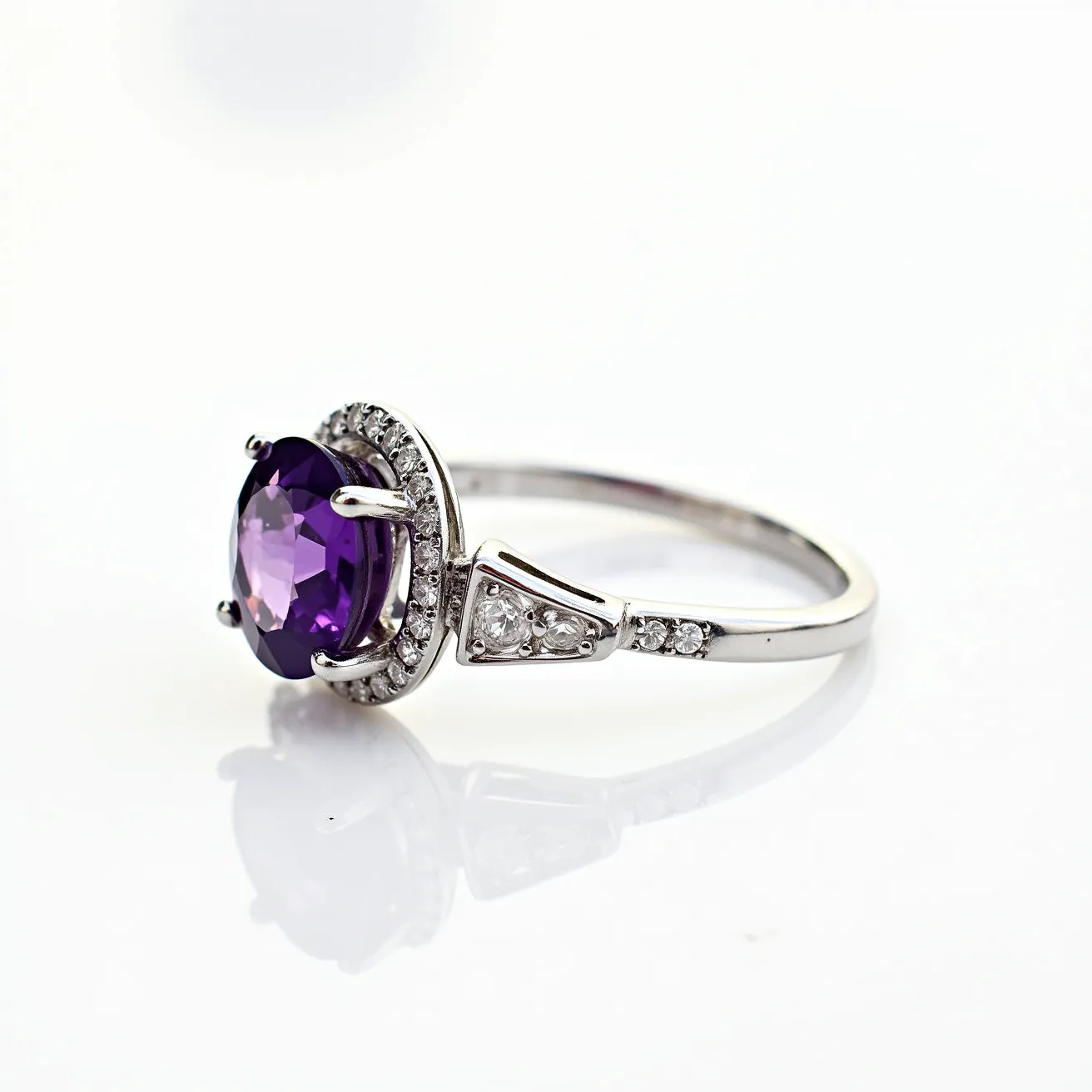 This amethyst promise ring features a stunning, oval-cut amethyst as the centerpiece, set in a secure prong setting. The vibrant purple gemstone is surrounded by a halo of small, sparkling round diamonds that enhance its elegance and brilliance. The ring is crafted from polished white gold or silver, providing a sleek and sophisticated foundation. The band itself is adorned with additional small diamonds set intricately along the shoulders, tapering towards the central gemstone. This exquisite design emphasizes the beauty of the amethyst while adding a touch of timeless elegance.